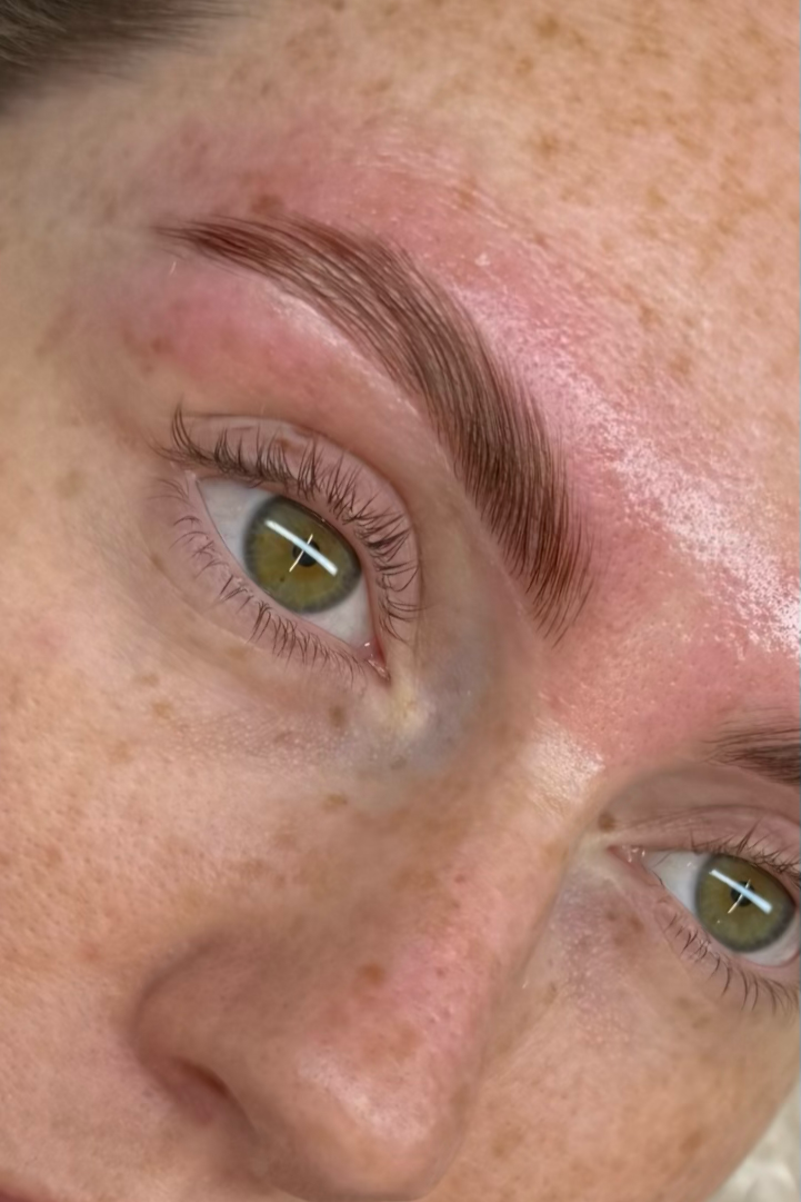 Close-up of a person's face with well-groomed eyebrows, light freckles, and hazel eyes.