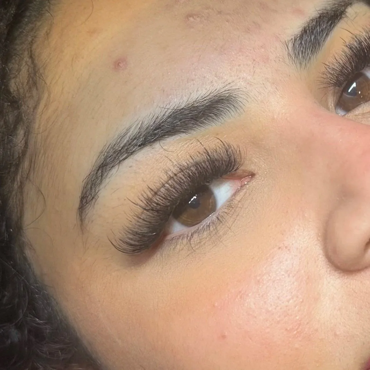 Close-up of a woman's eye with makeup, including long, curled eyelashes and well-defined eyebrows.