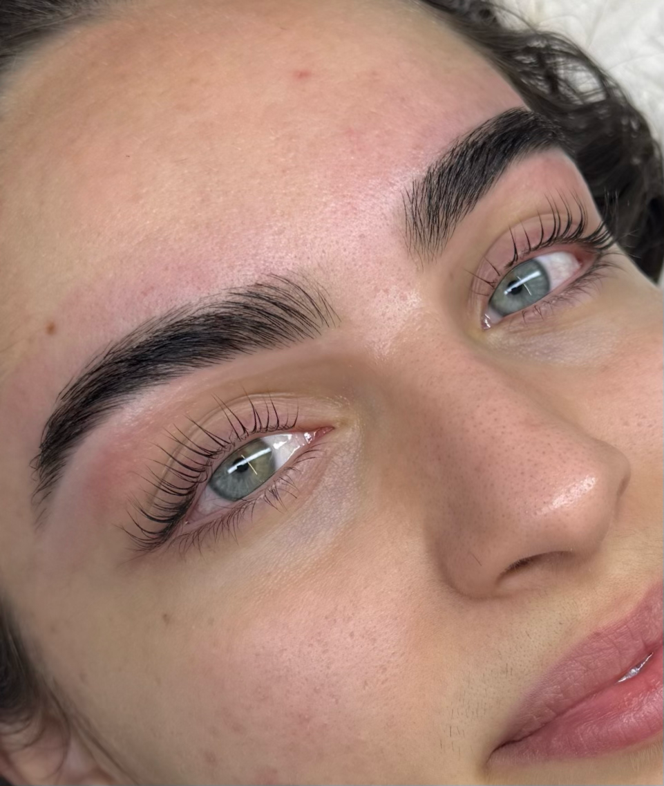 Close-up of a woman's face showing freshly done eyelash extensions and well-groomed eyebrows.