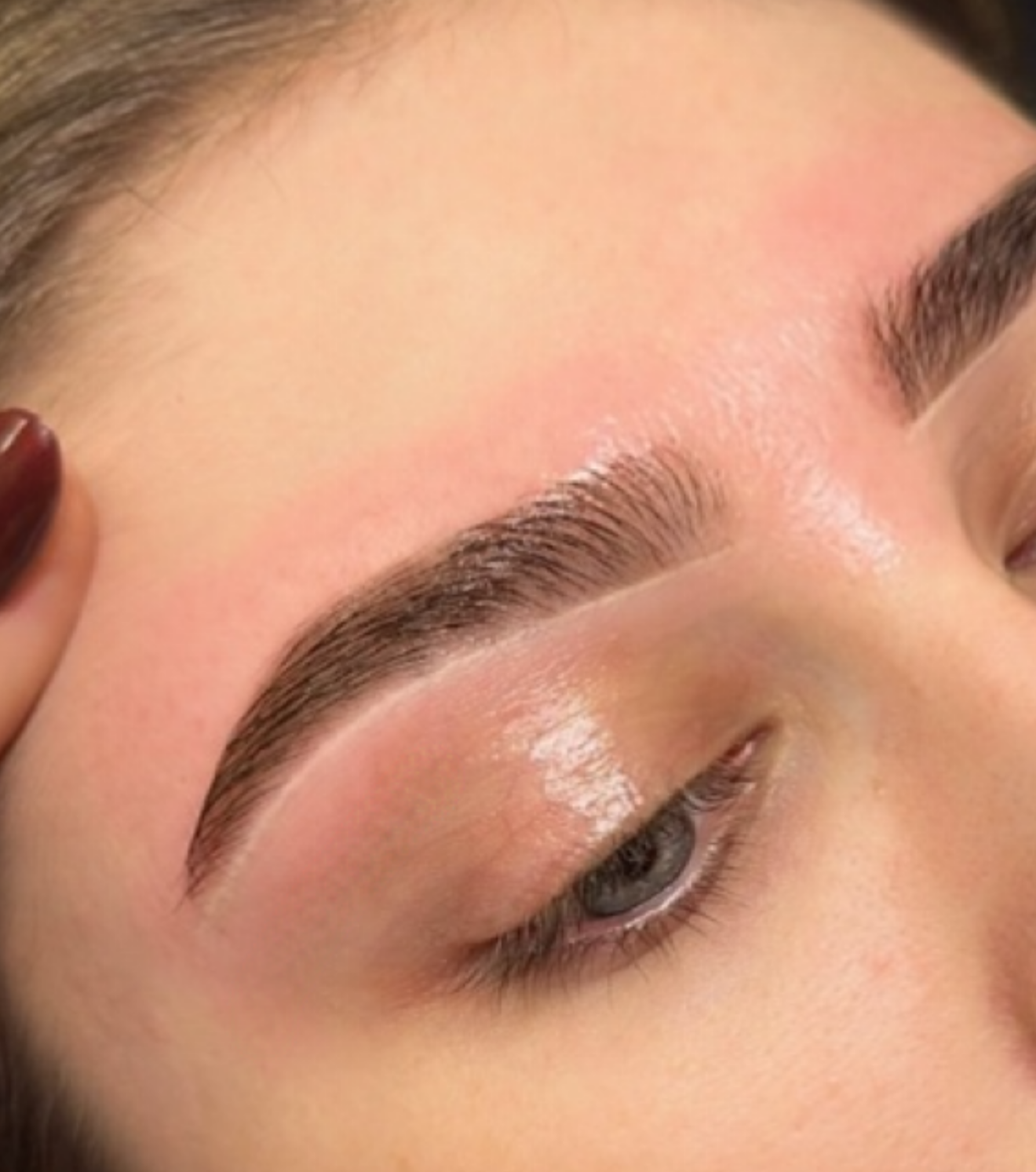 Close-up of a person's eye with groomed eyebrows, subtle makeup, and smooth skin.