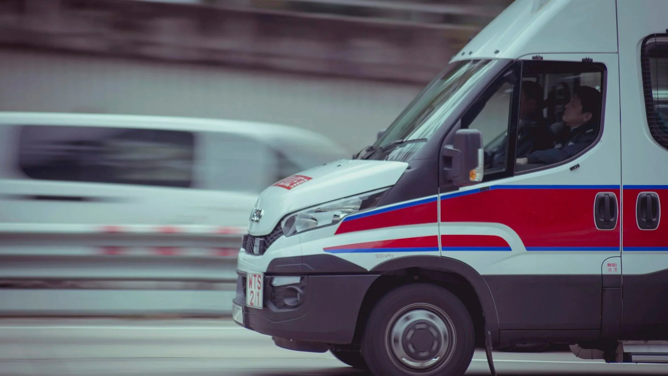 An ambulance driving on the highway with a blurred background.