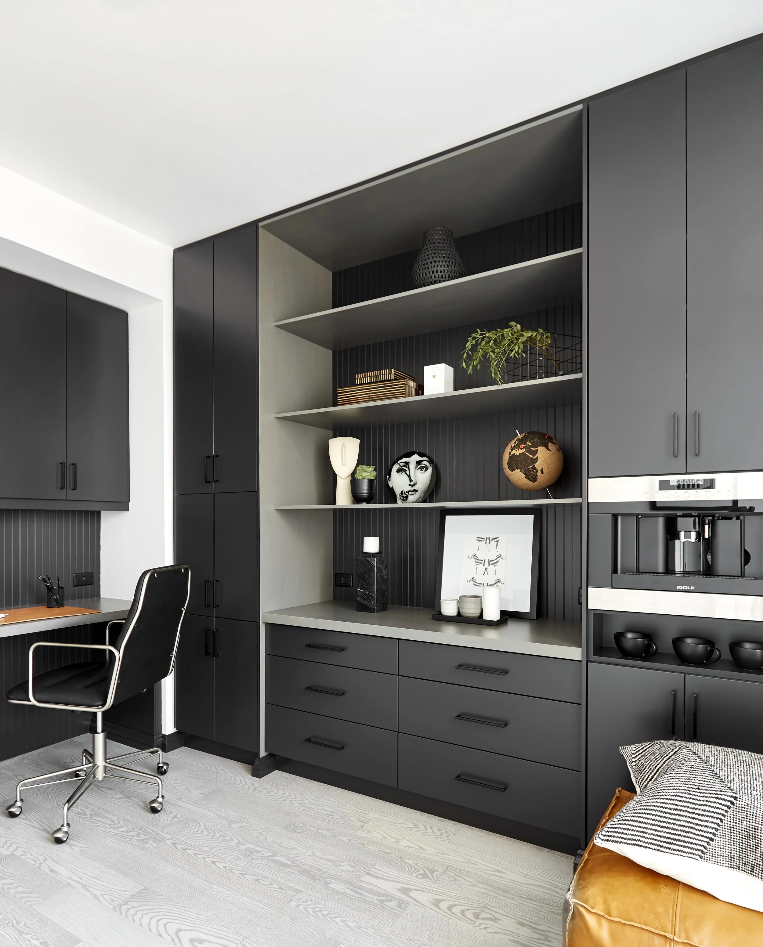 Modern kitchen with black cabinetry and open shelving displaying decor and artwork