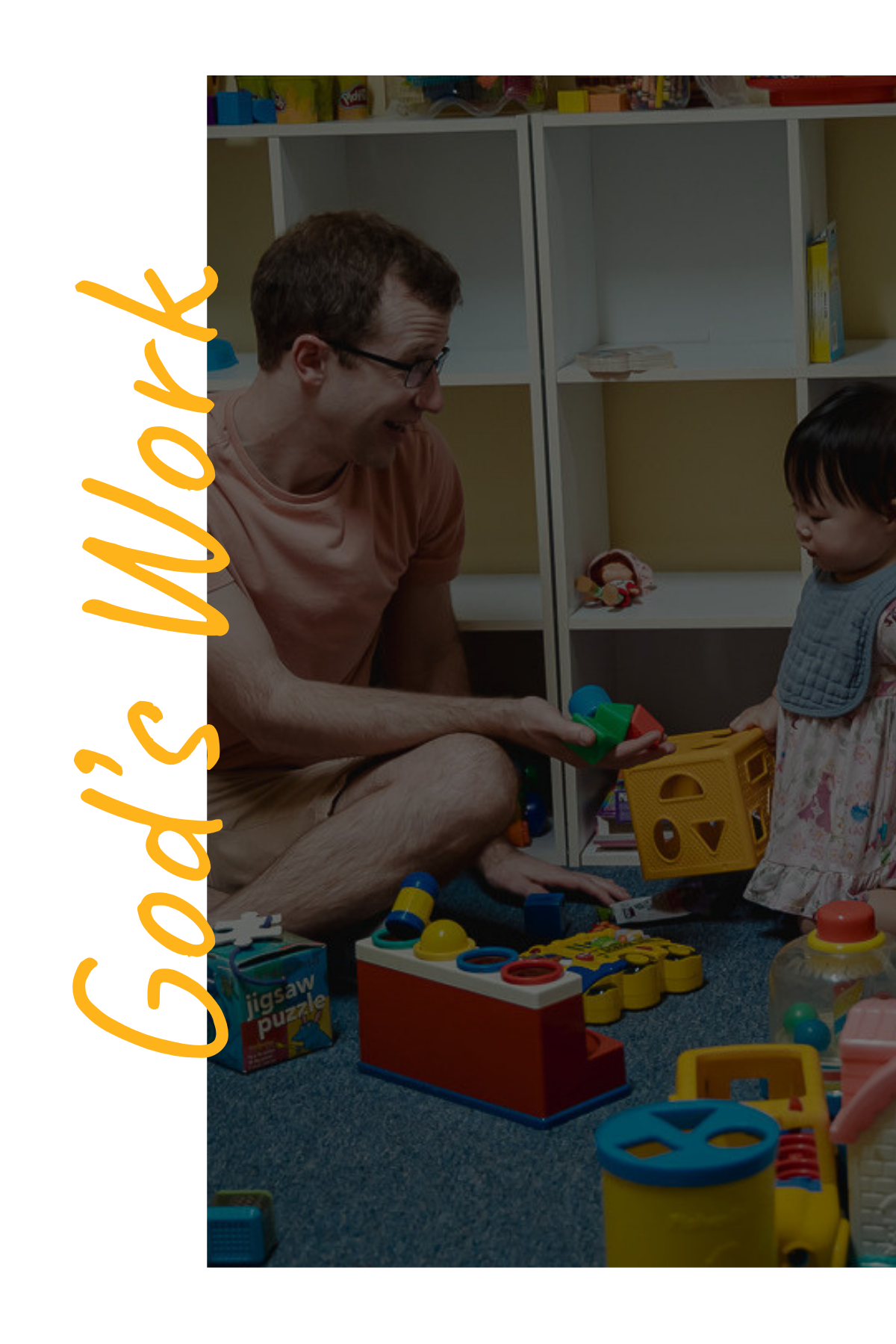 A man and young girl playing with colorful toys on a blue carpeted floor, surrounded by shelves and scattered toys.