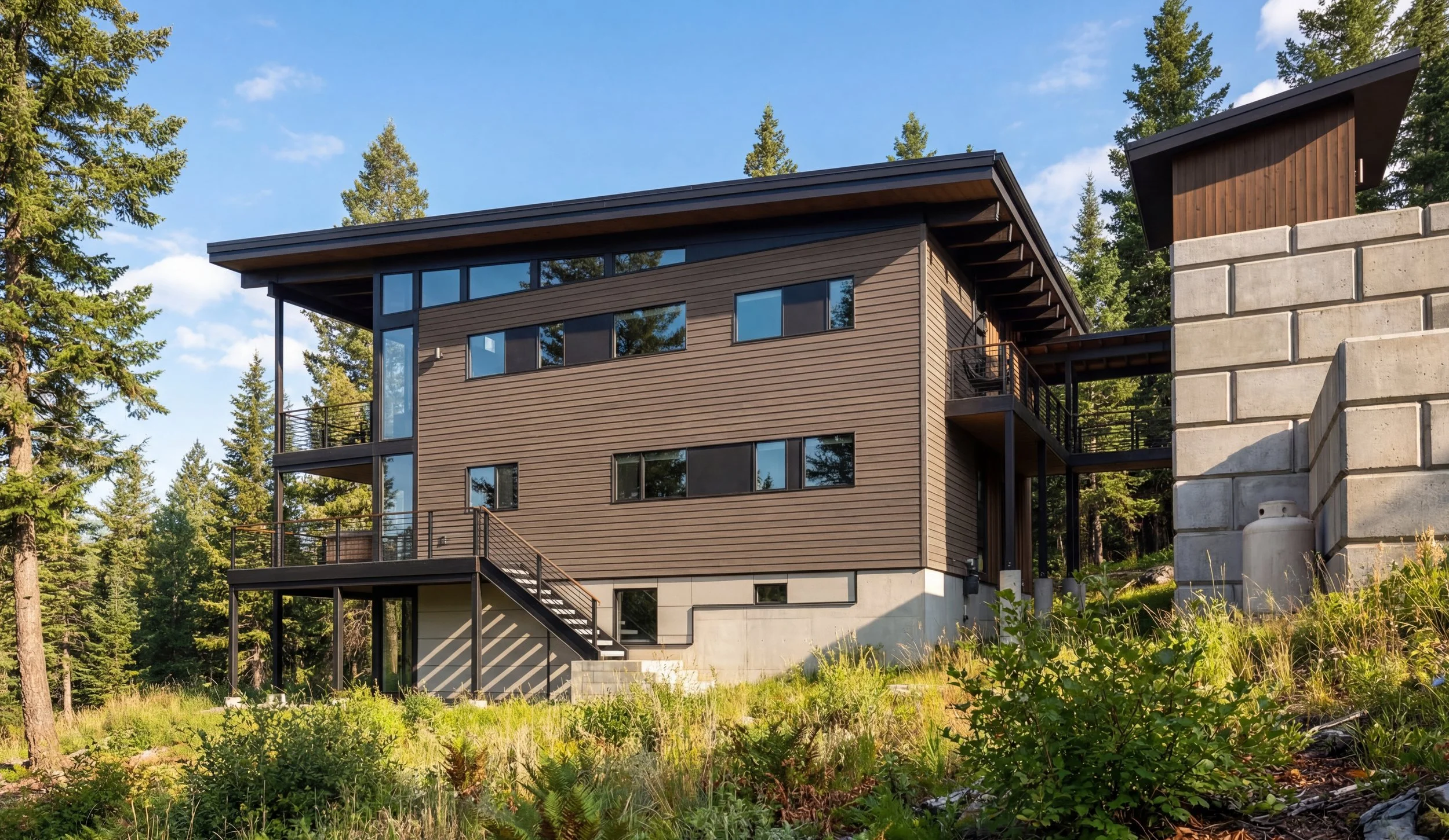 World Cup 2026 Seattle large group rental Modern multi-story house with wooden siding, large windows, and balconies, set in a forested area with lush greenery.