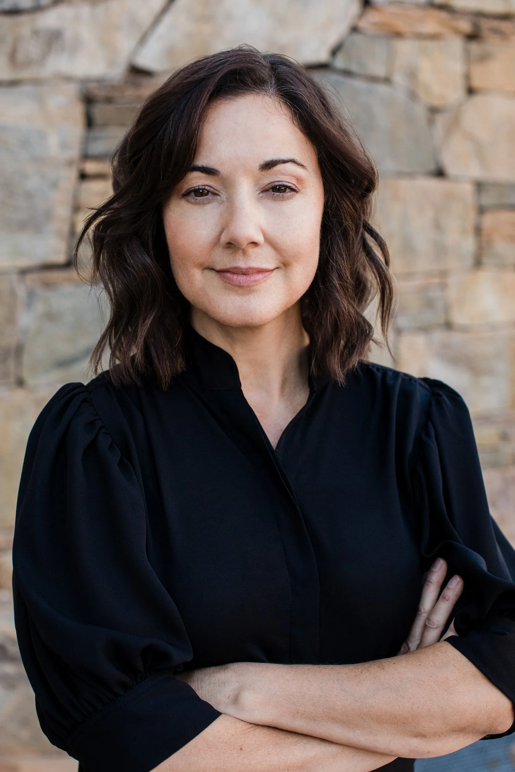 Kristen Calhoun, Upstate SC vocal coach and speech therapist, posing against a beige stone wall.