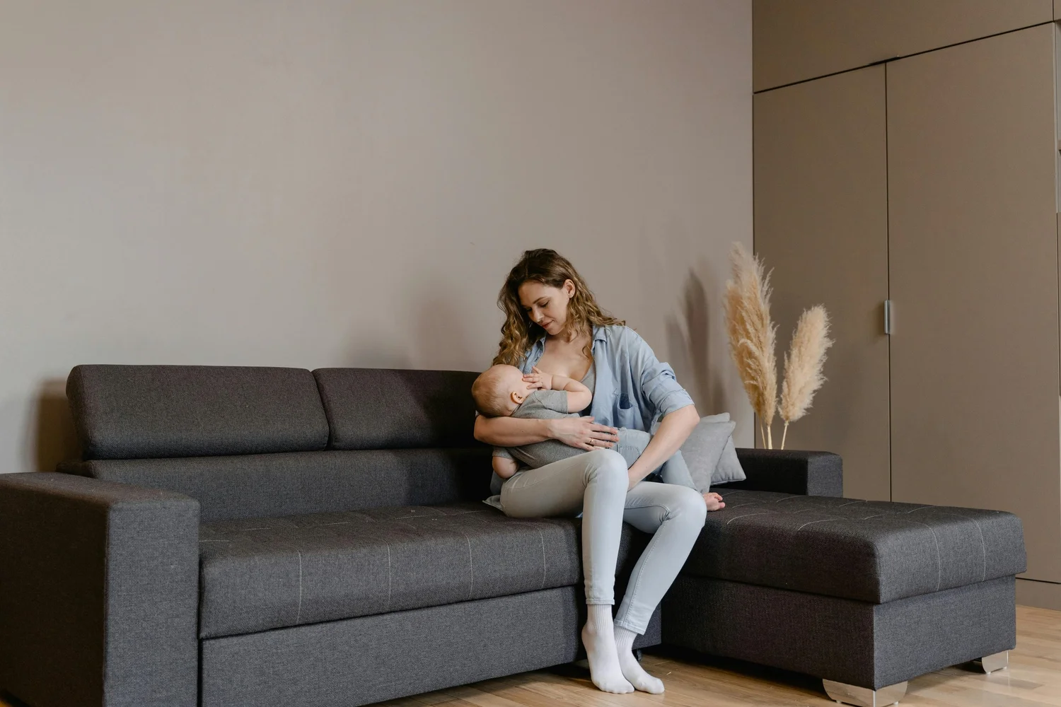 A mother nursing her baby on a sofa