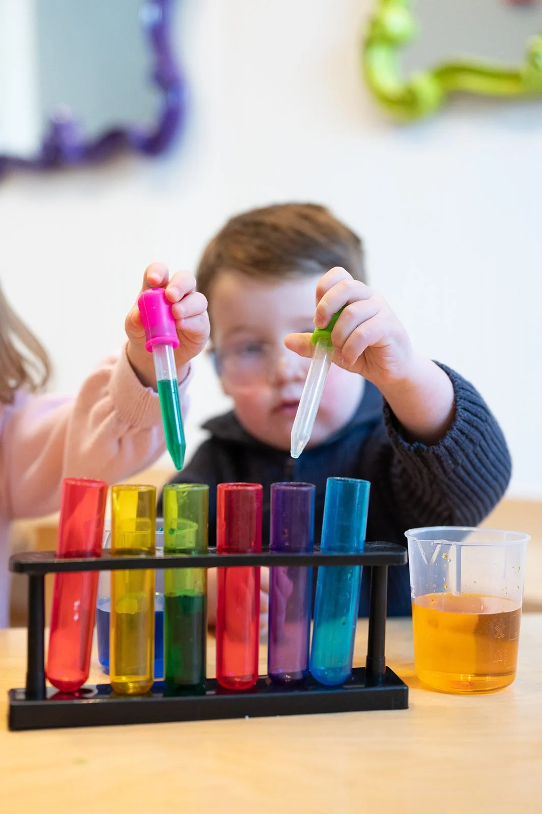 Children conducting a science experiment with colorful test tubes and liquids.