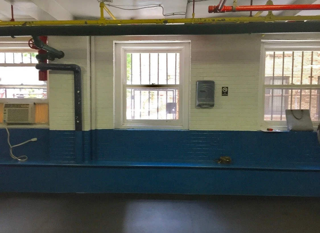 Interior view of a room with a window, an air conditioning unit, and black and yellow pipes running along the ceiling.