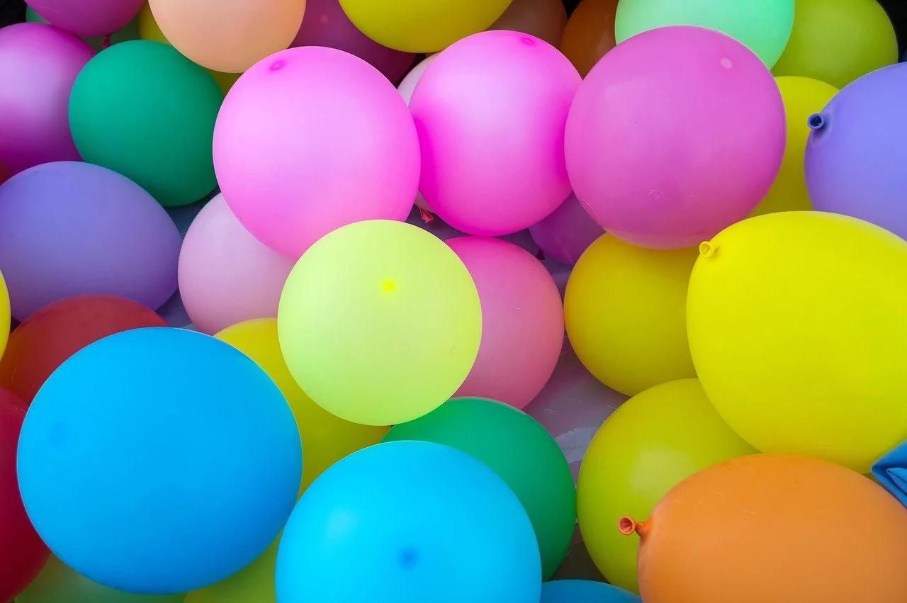 Colorful balloons in pink, yellow, green, blue, purple, and orange stacked together.