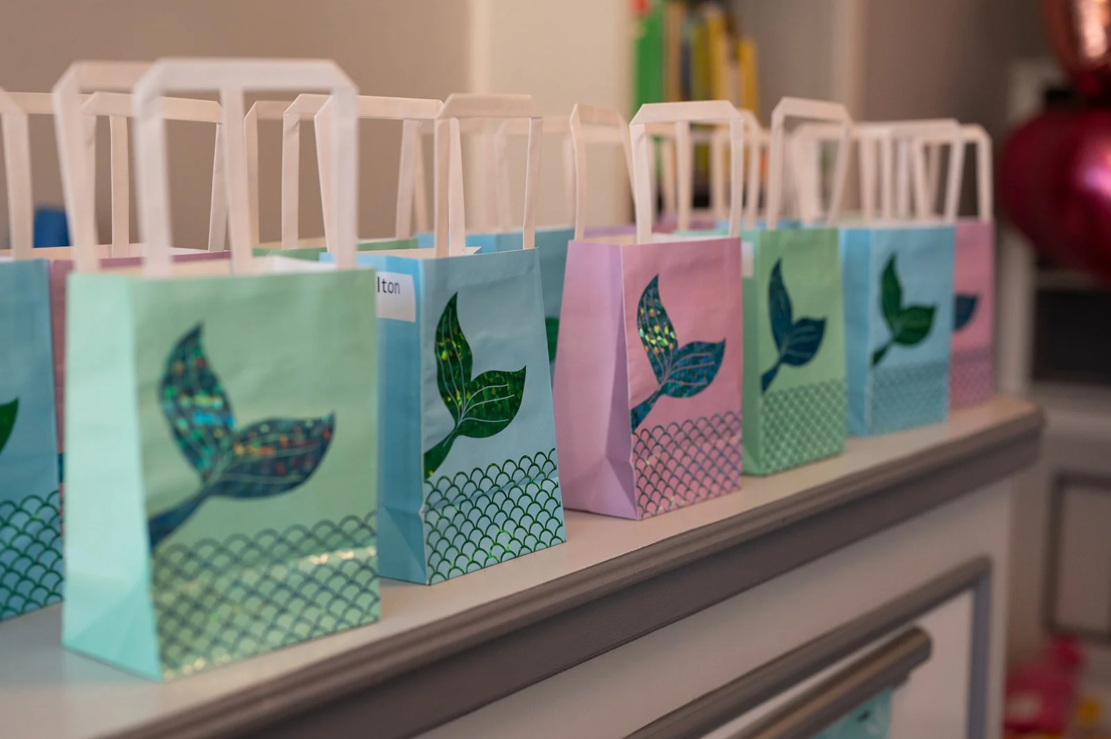 Colorful gift bags with leaf designs arranged on a shelf, likely for a celebration or event.