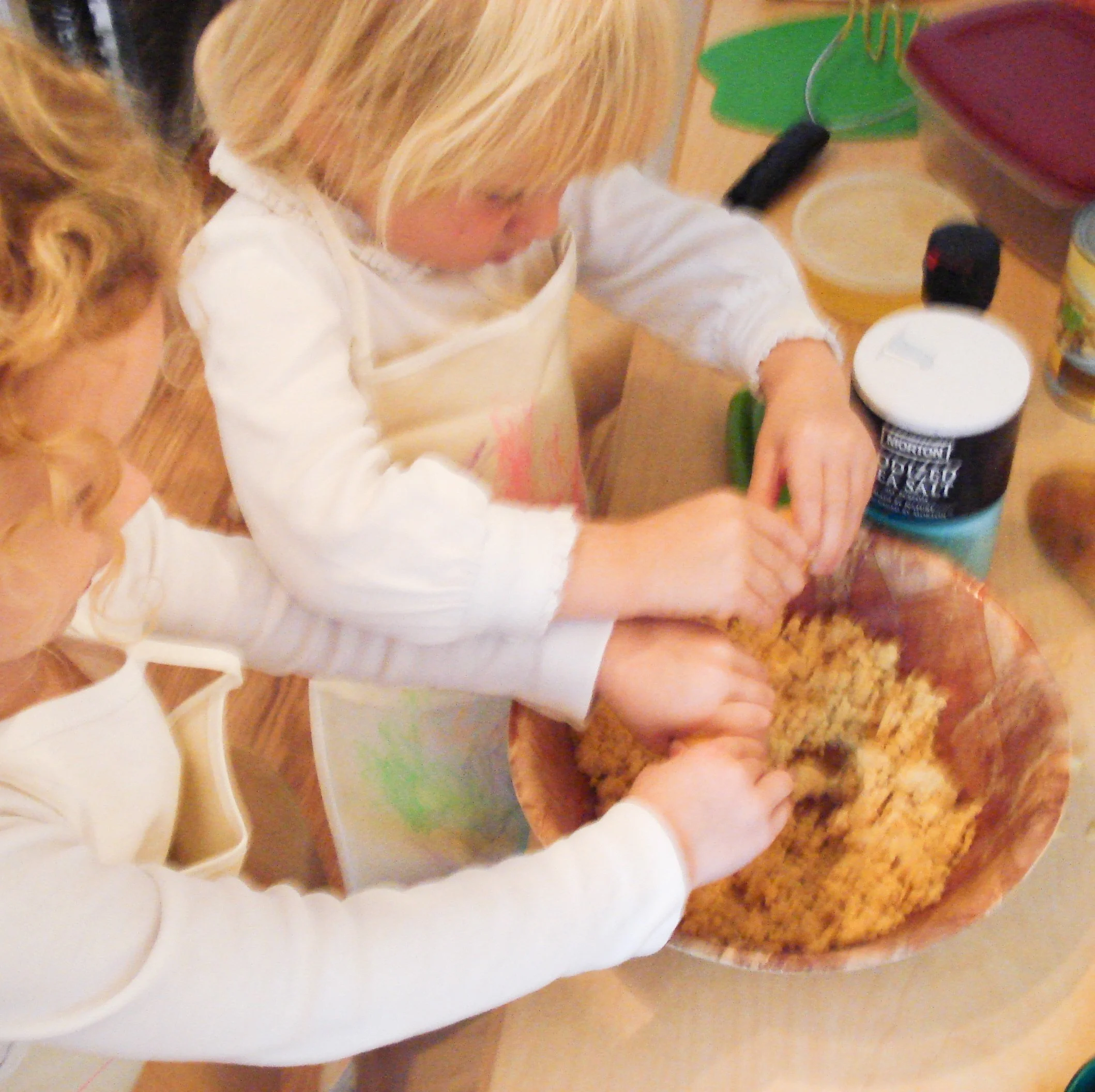Two young girls mixing ingredients in a large bowl in a kitchen.