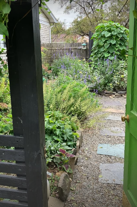 AFTER: A "secret" space planted in shades of green, blue, purple, and white, with gravel pathways, and a Moonflower-planted tower in the middle.
