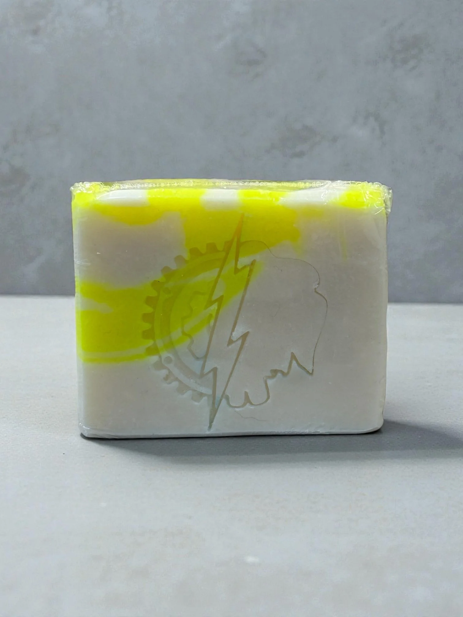 Single bar of yellow and white swirled soap sitting on a marble counter top.