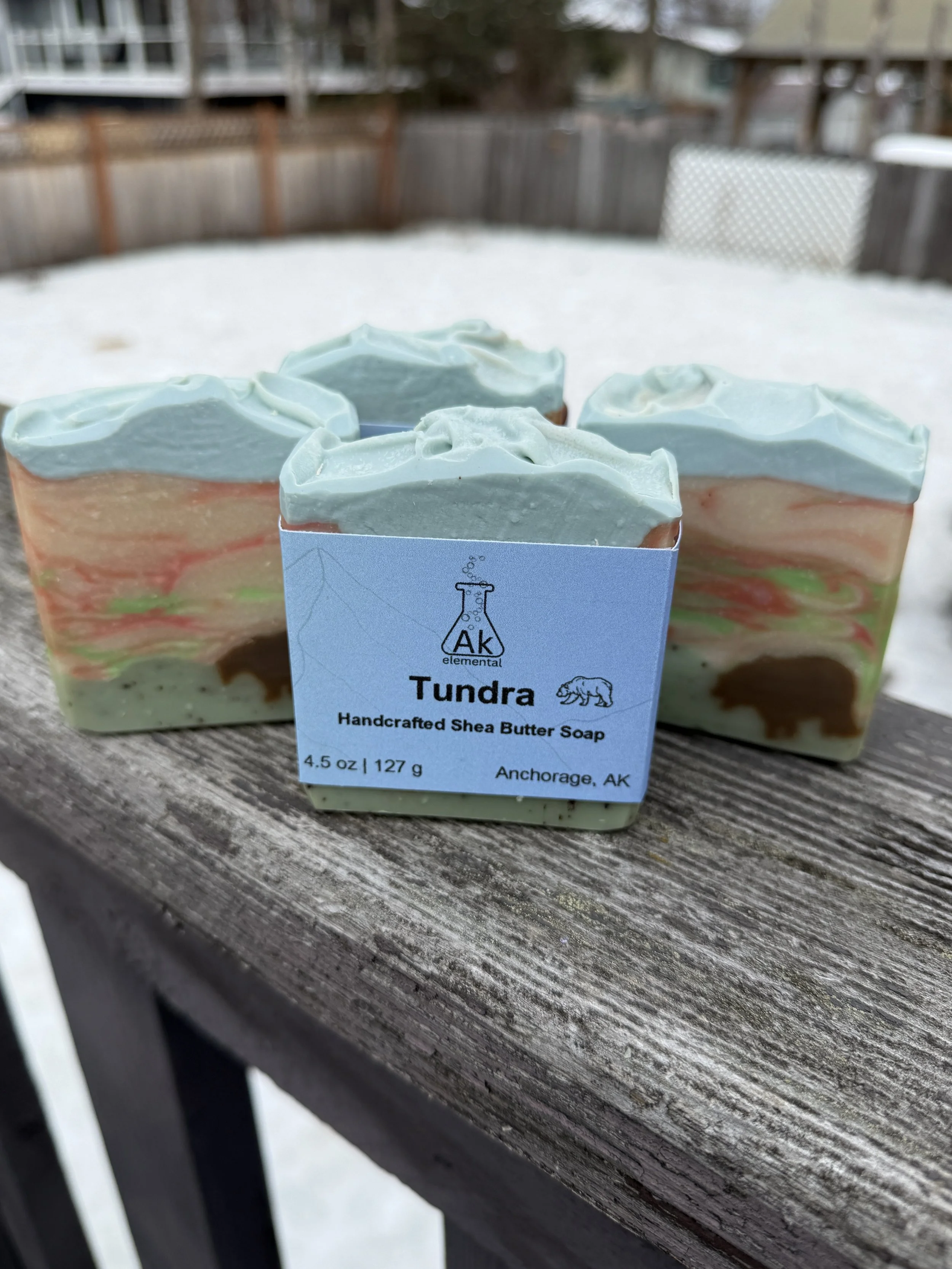 Rectangular soap bar with avocado oil, coconut milk, and bear embed, styled outdoors in snowy Alaska setting