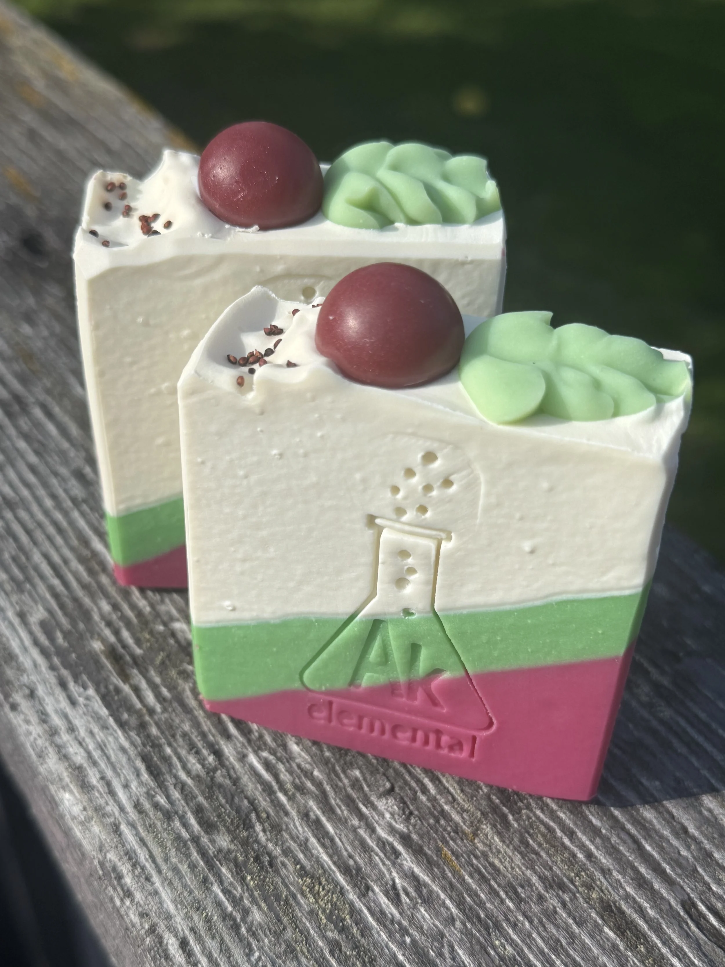 Handcrafted Wild Cranberry soap bar with cream, evergreen green and cranberry red diagonal layers and festive round soap embeds on top.