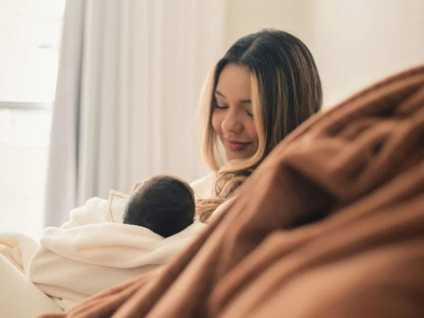 A woman cradles her sleeping baby how to balance hormones postpartum