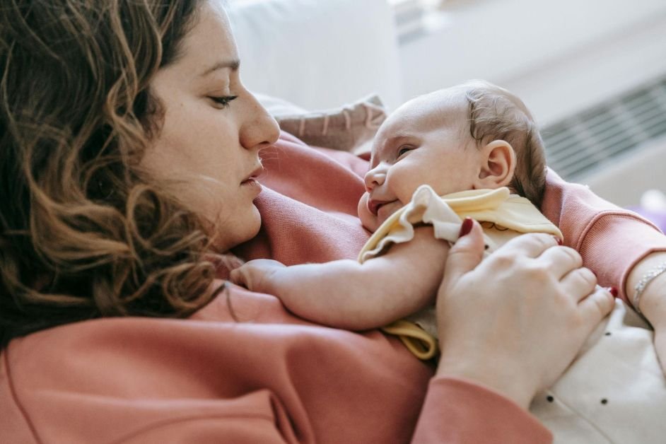 Woman lovingly cradles a sleeping baby postpartum depression awareness color