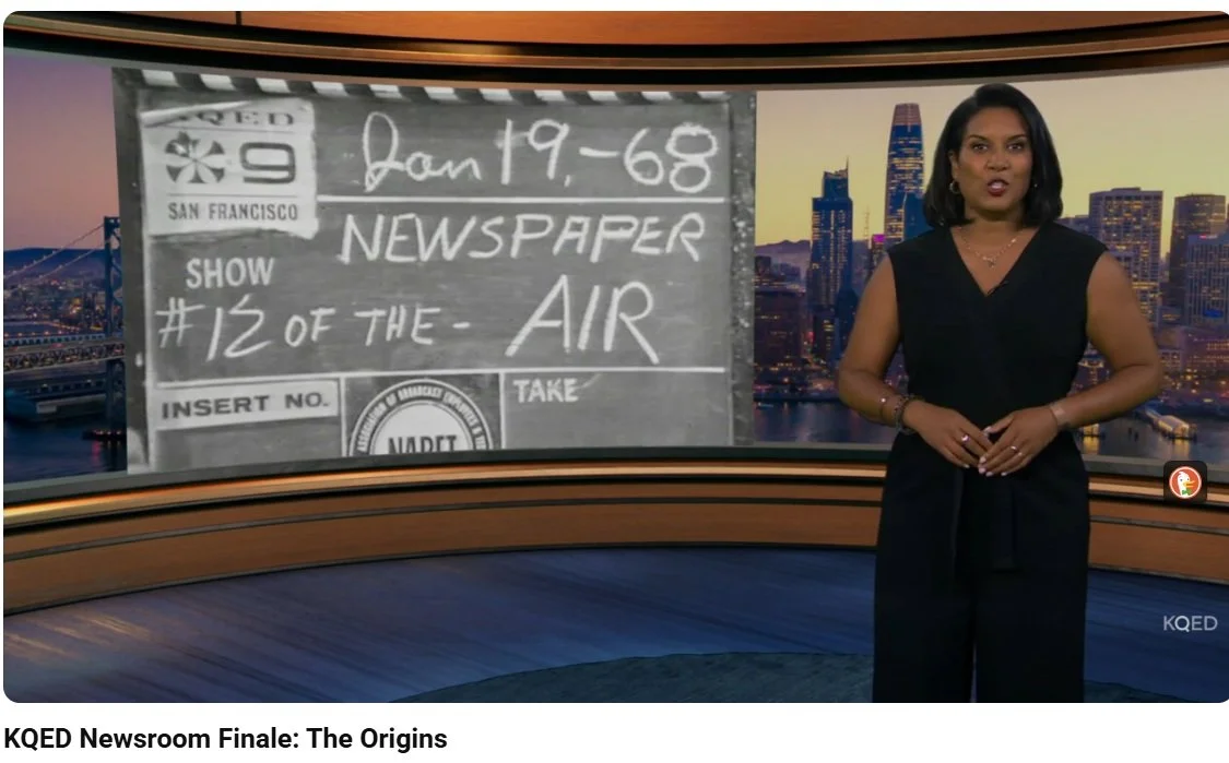 A female news anchor standing in front of a large screen displaying a black and white image of a newspaper clipping with handwritten notes, in a newsroom with a city skyline in the background.