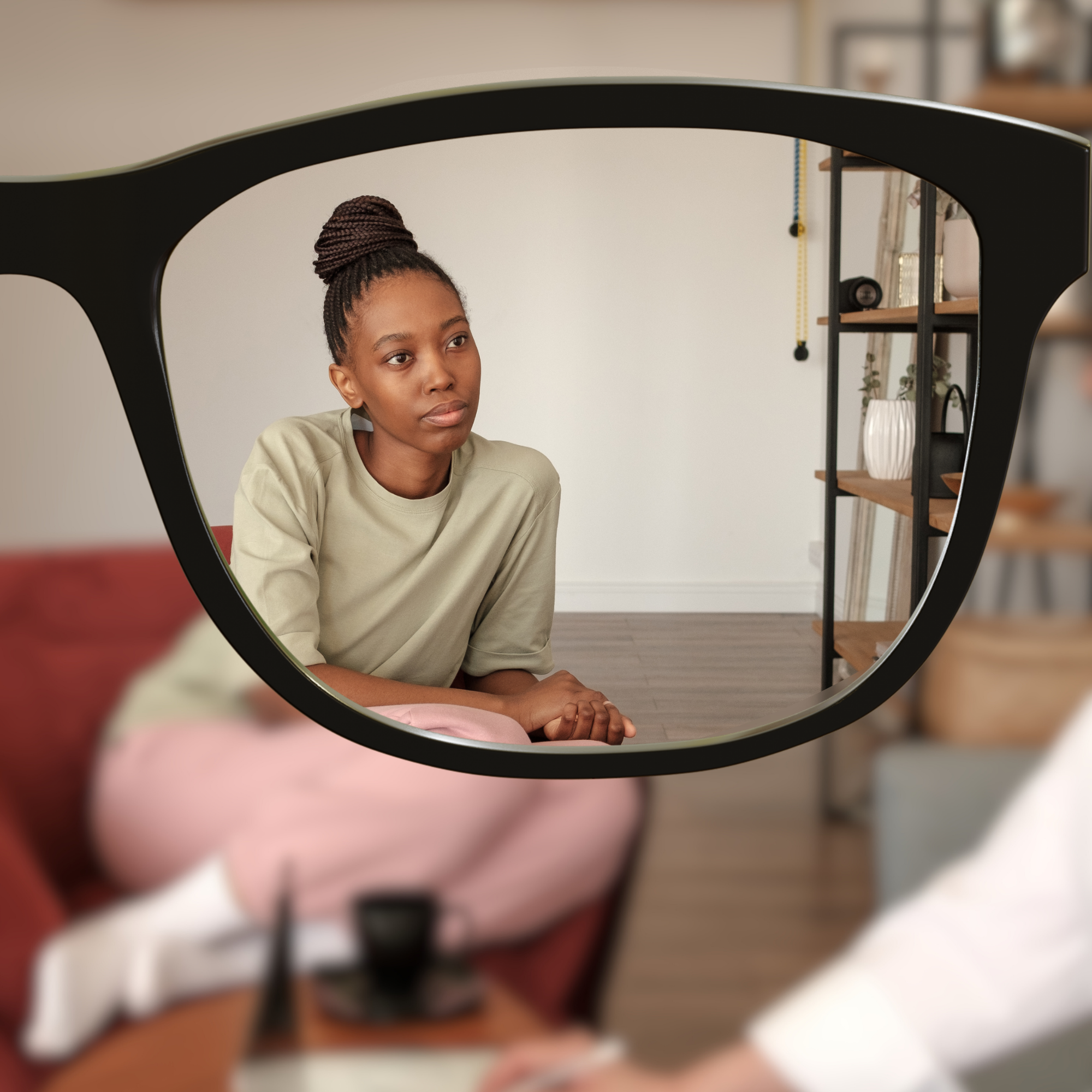 Young woman sitting on a couch, reflected in a large round mirror, with a neutral expression, in a modern living room.