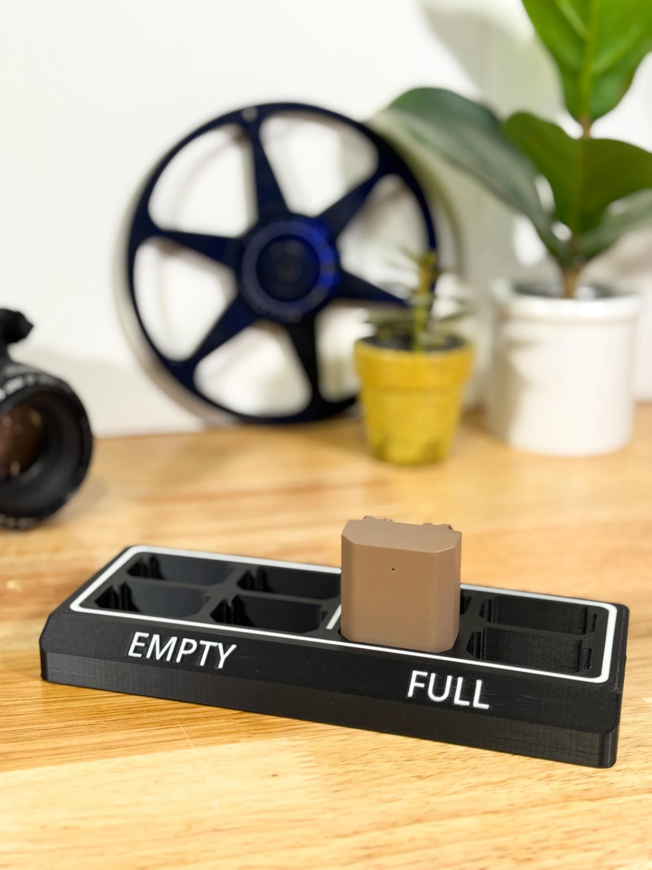 A tan square object on a black and white dashboard indicator marked 'EMPTY' on the left and 'FULL' on the right, placed on a wooden surface.
