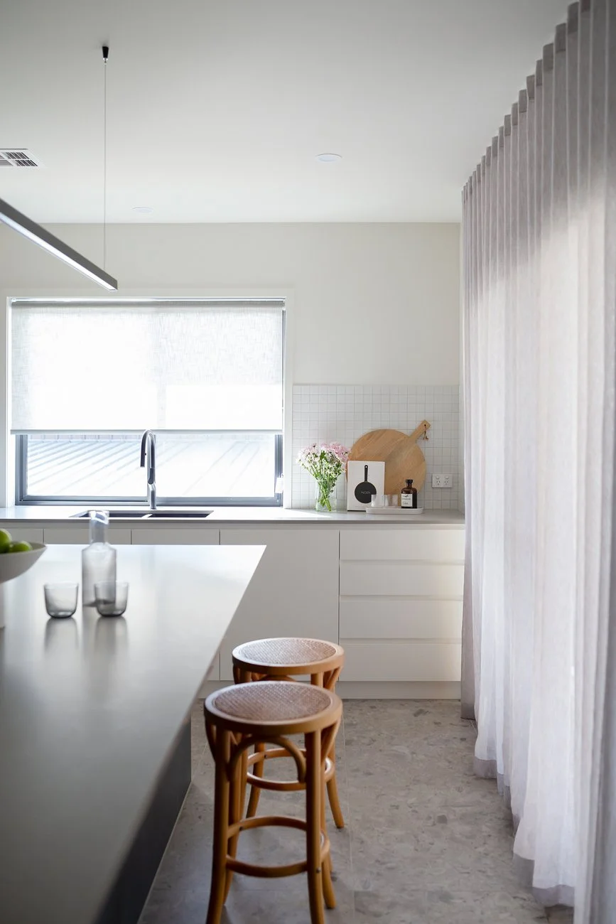 Family kitchen with bench seating, sheer curtains and ample storage by Banksia Projects