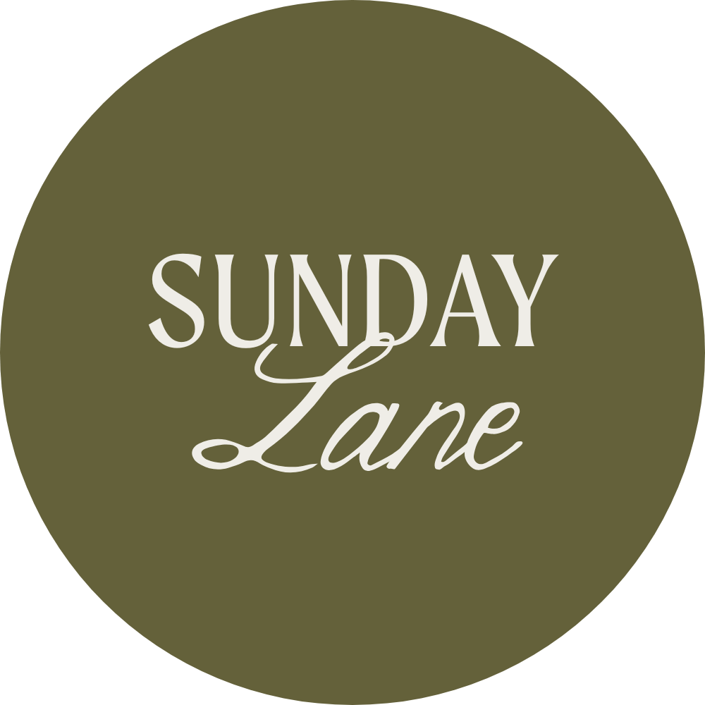 A circular logo with a dark olive green background and white text that reads 'Sunday Lane'.