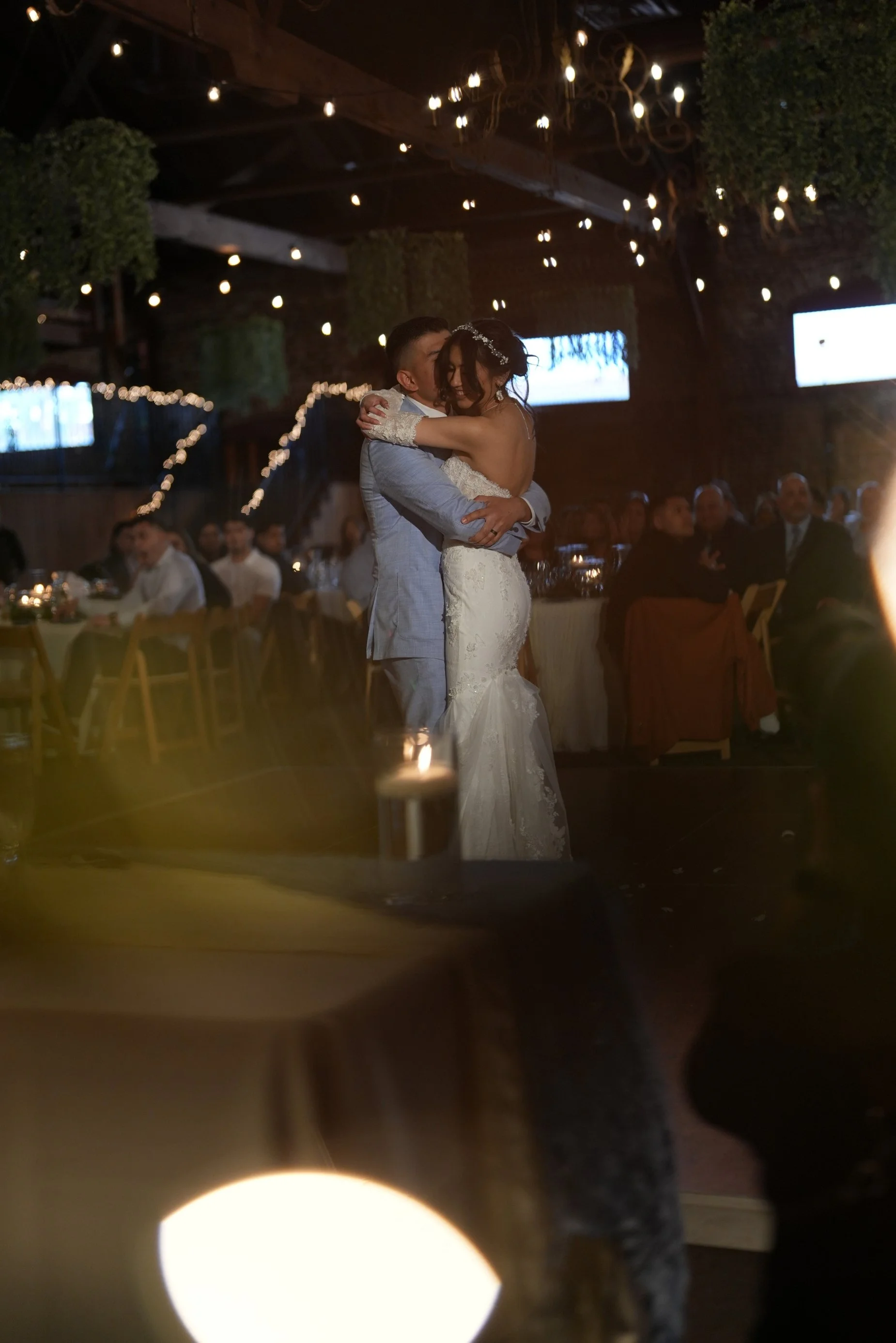bride and groom first dance under twinkling lights inside venue.jpg