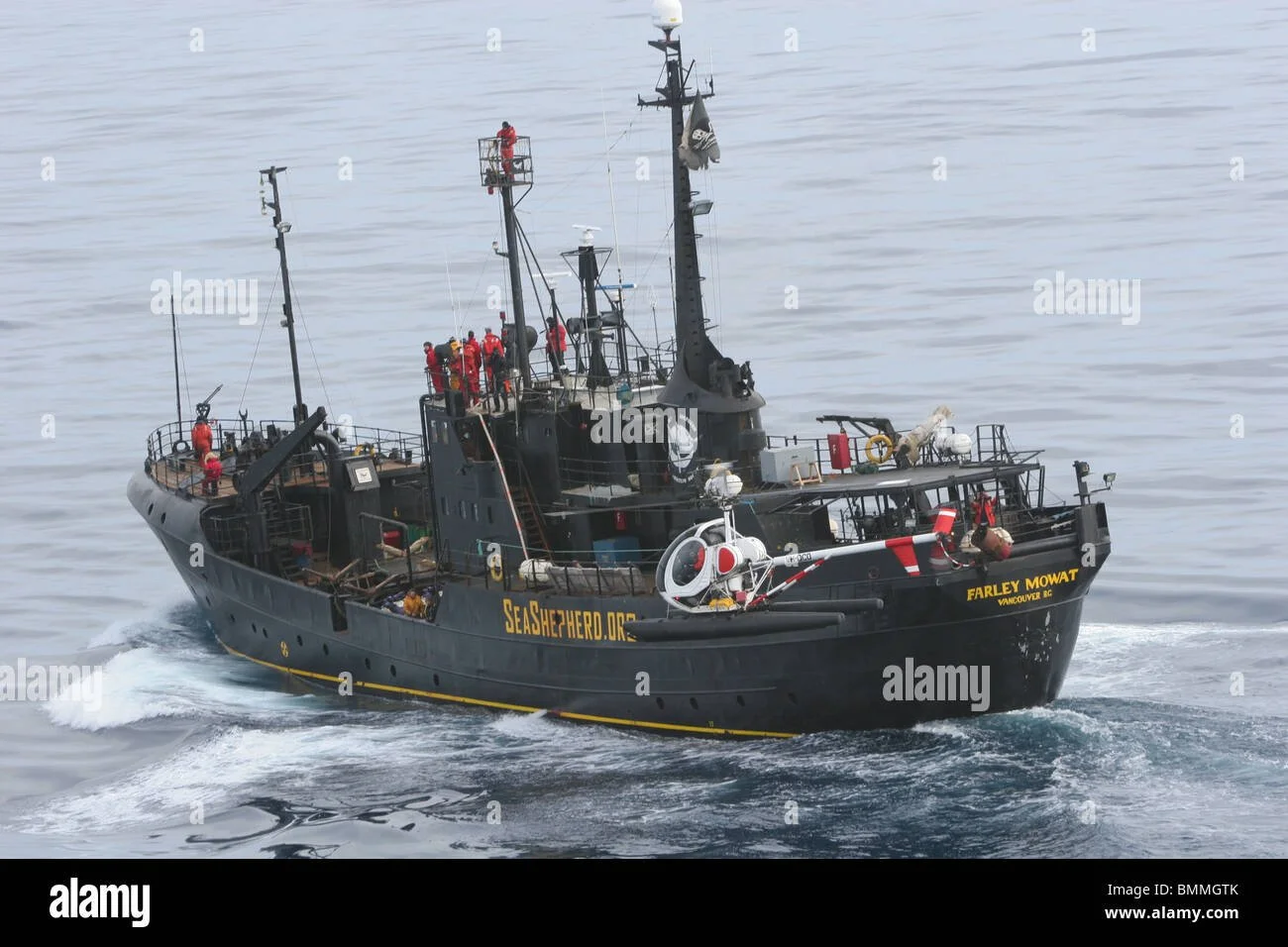 A large, black Sea Shepherd conservation vessel , activists on the deck of a ship