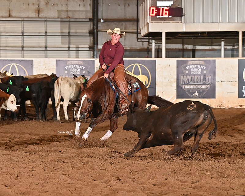 A cowgirl riding a chestnut cutting horse in an indoor arena with a digital timer displaying 0:16 in the background.