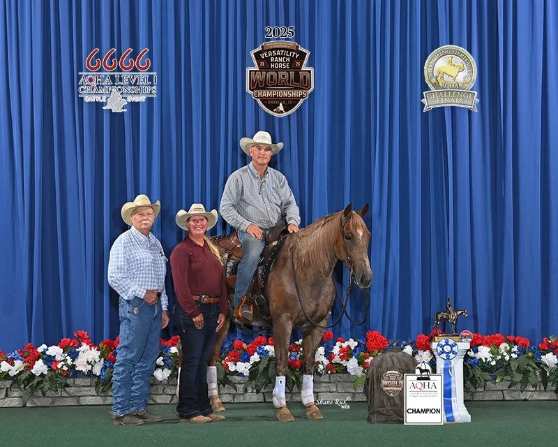 Three people, two women and one man, with the man sitting on a horse, in front of a blue curtain decorated with rodeo event logos, including 'Versatility Ranch Horse World Championships 2025.' The scene is at an awards ceremony with flowers, trophies, and ribbons.