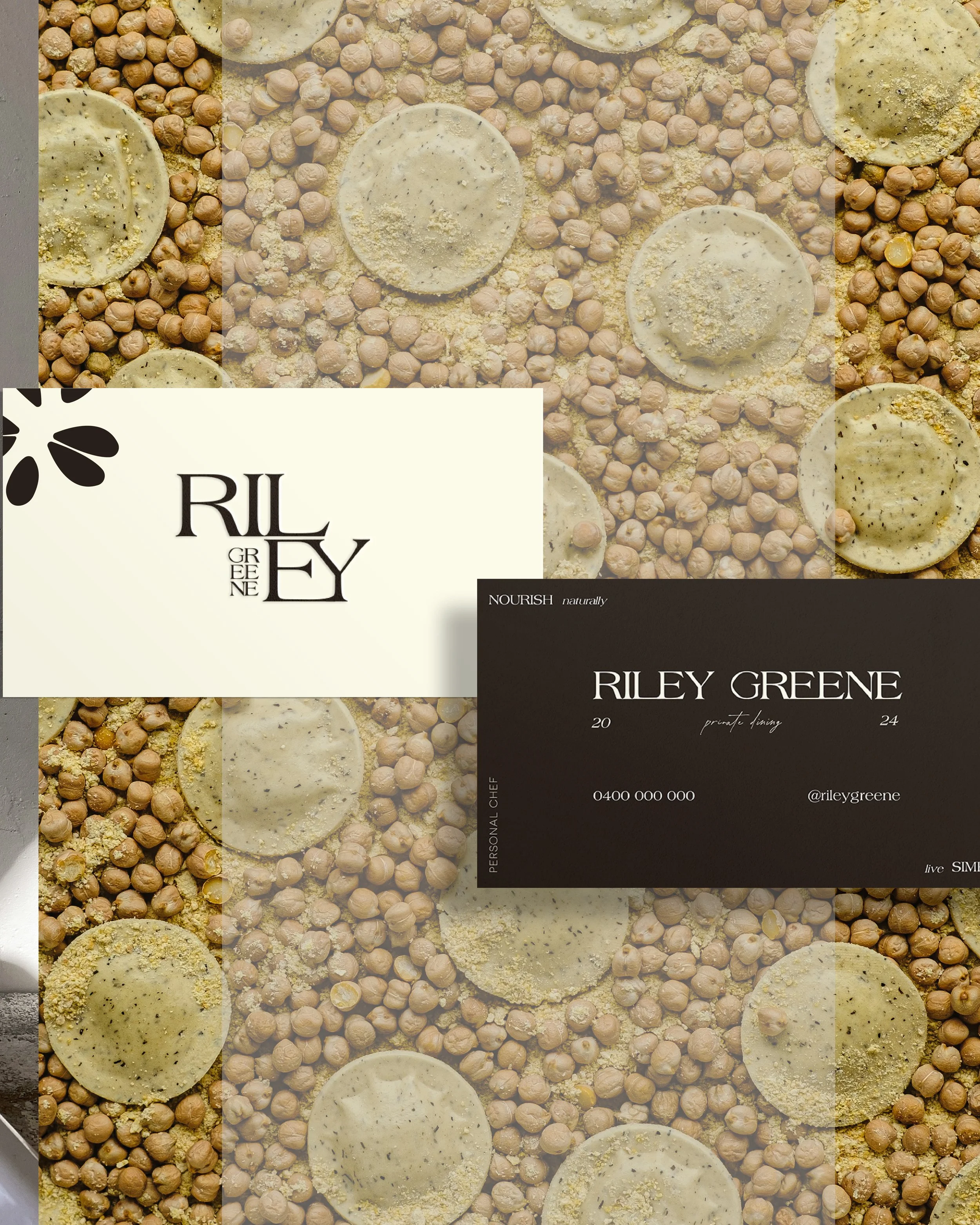 Close-up of a business card placed on a surface covered with chickpeas and circular flatbread topped with black seeds and spices.