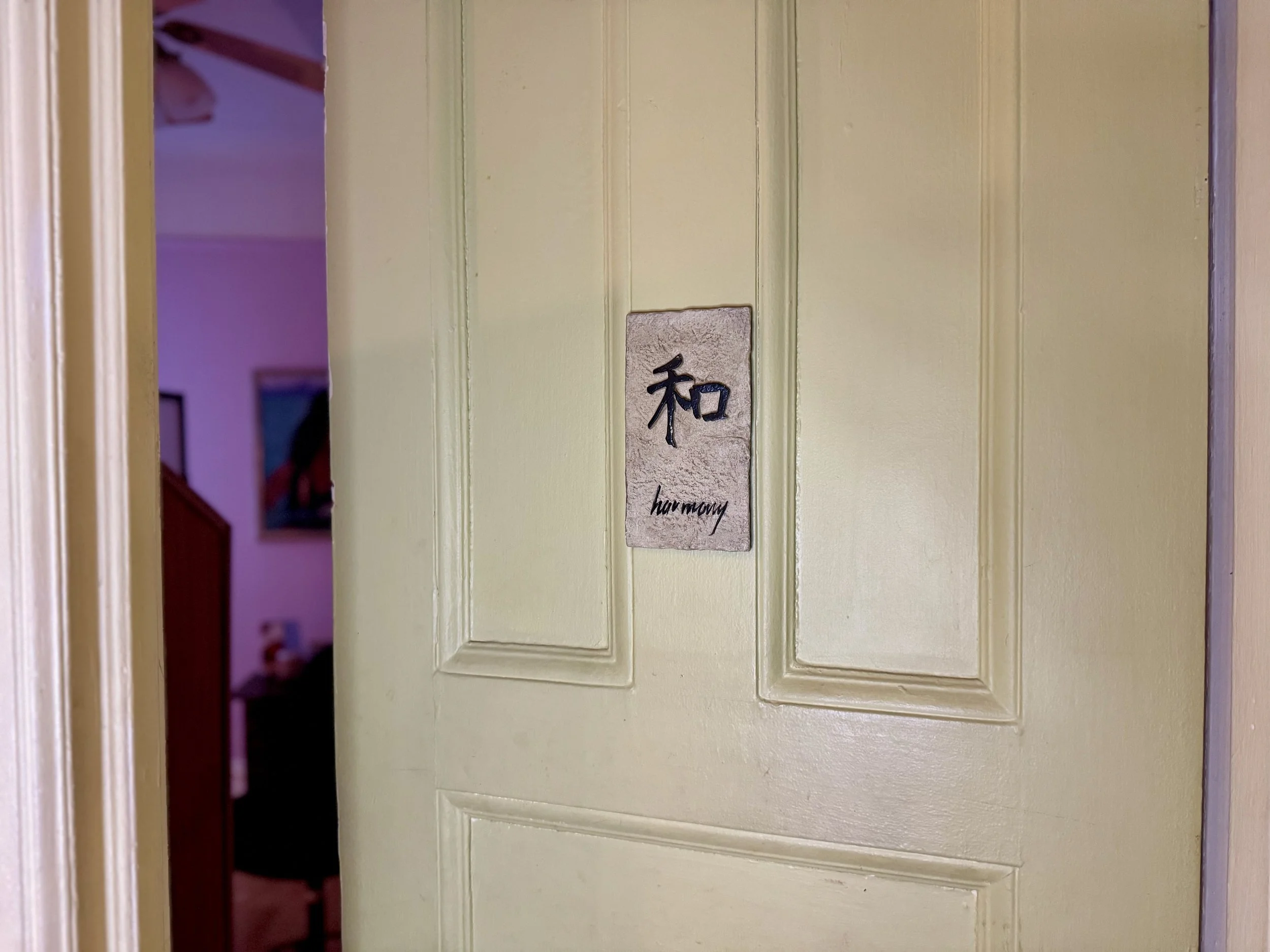 A yellow door with a sign that says "harmony" in English and has a Japanese character for harmony above it.