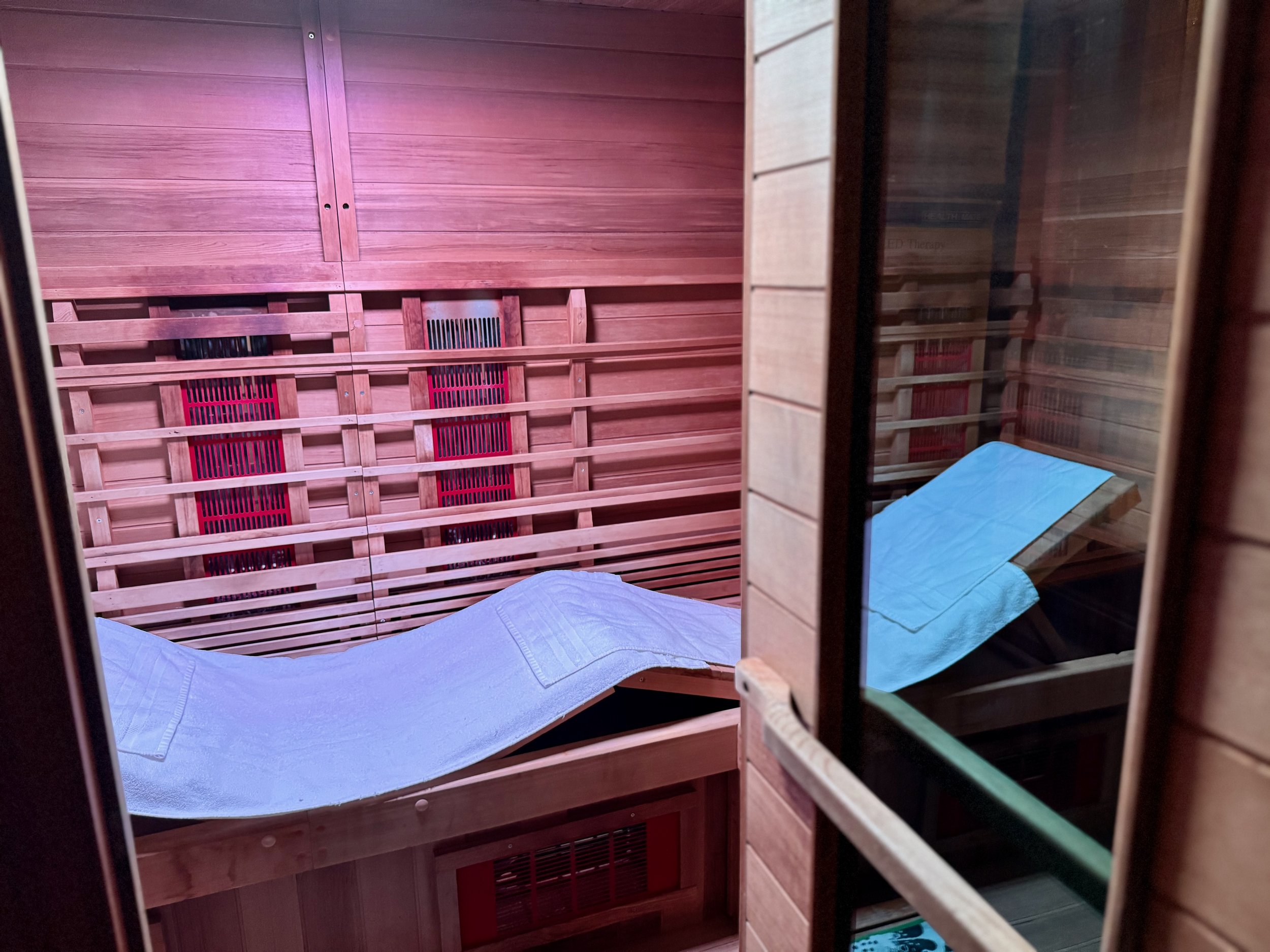 Inside a wooden sauna with a hammock and a mirror reflecting part of the sauna's interior.