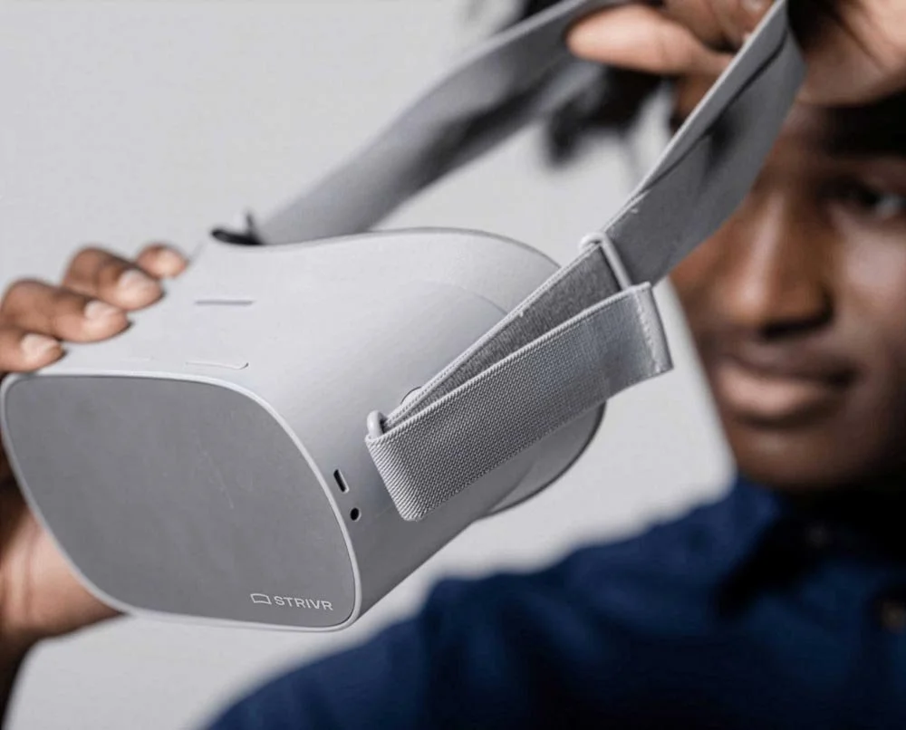 Person putting on a Strivr-branded VR headset for enterprise training.