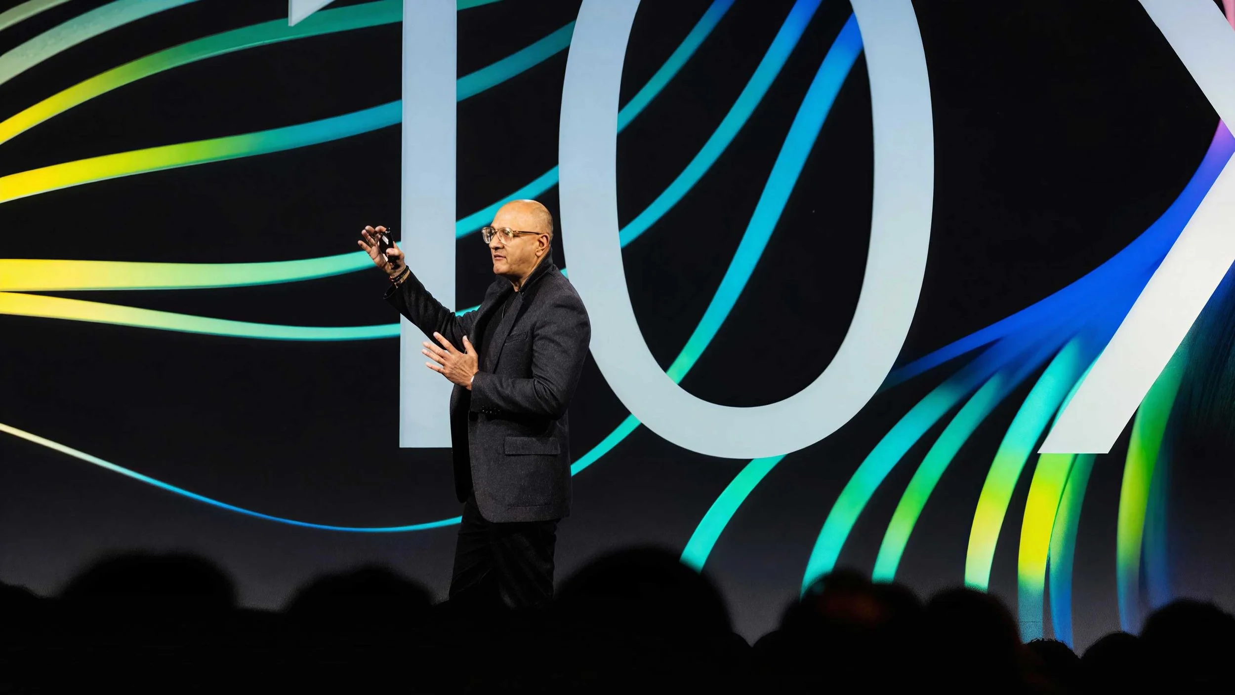 Presenter on stage at WebexOne 2024 keynote against abstract colorful backdrop.