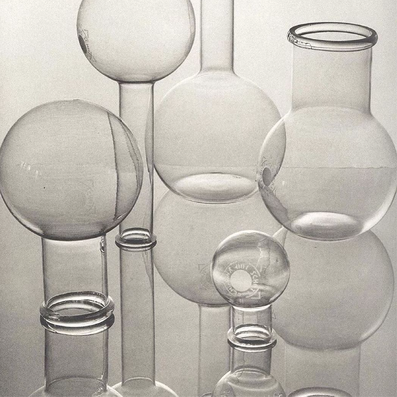 Collection of transparent glass vases and globes with reflections on a smooth surface.