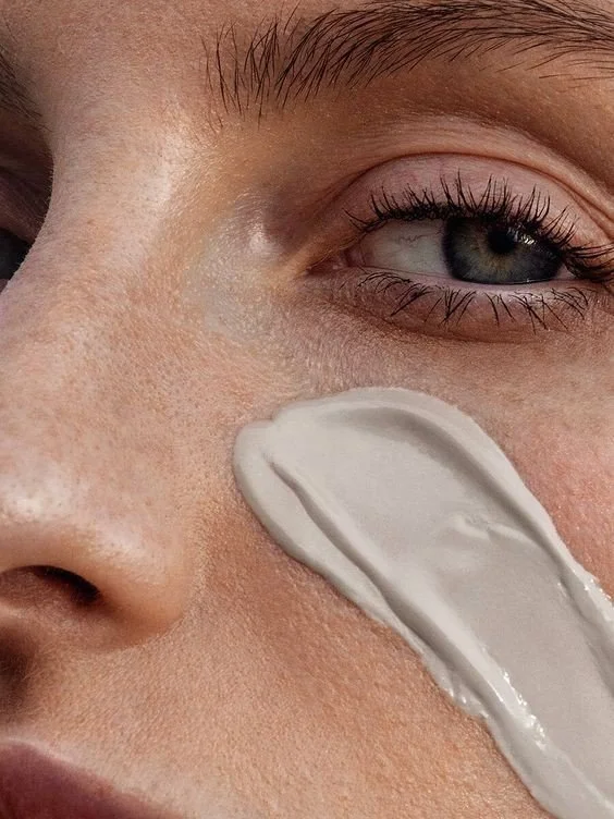 Close-up of a person's face with lotion applied to their cheek.