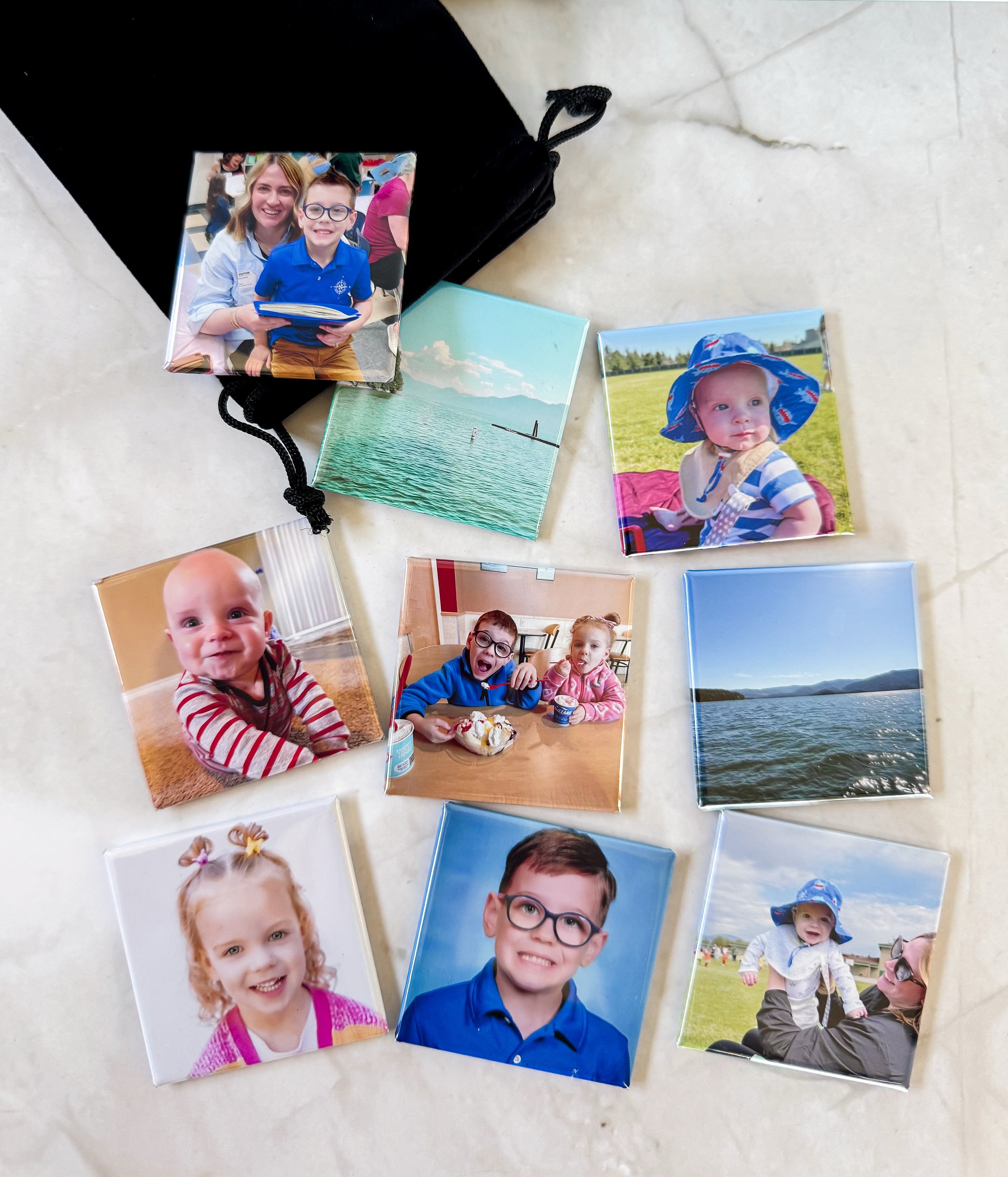 Collection of printed photographs depicting children, adults, and outdoor scenes, scattered on a light-colored surface.