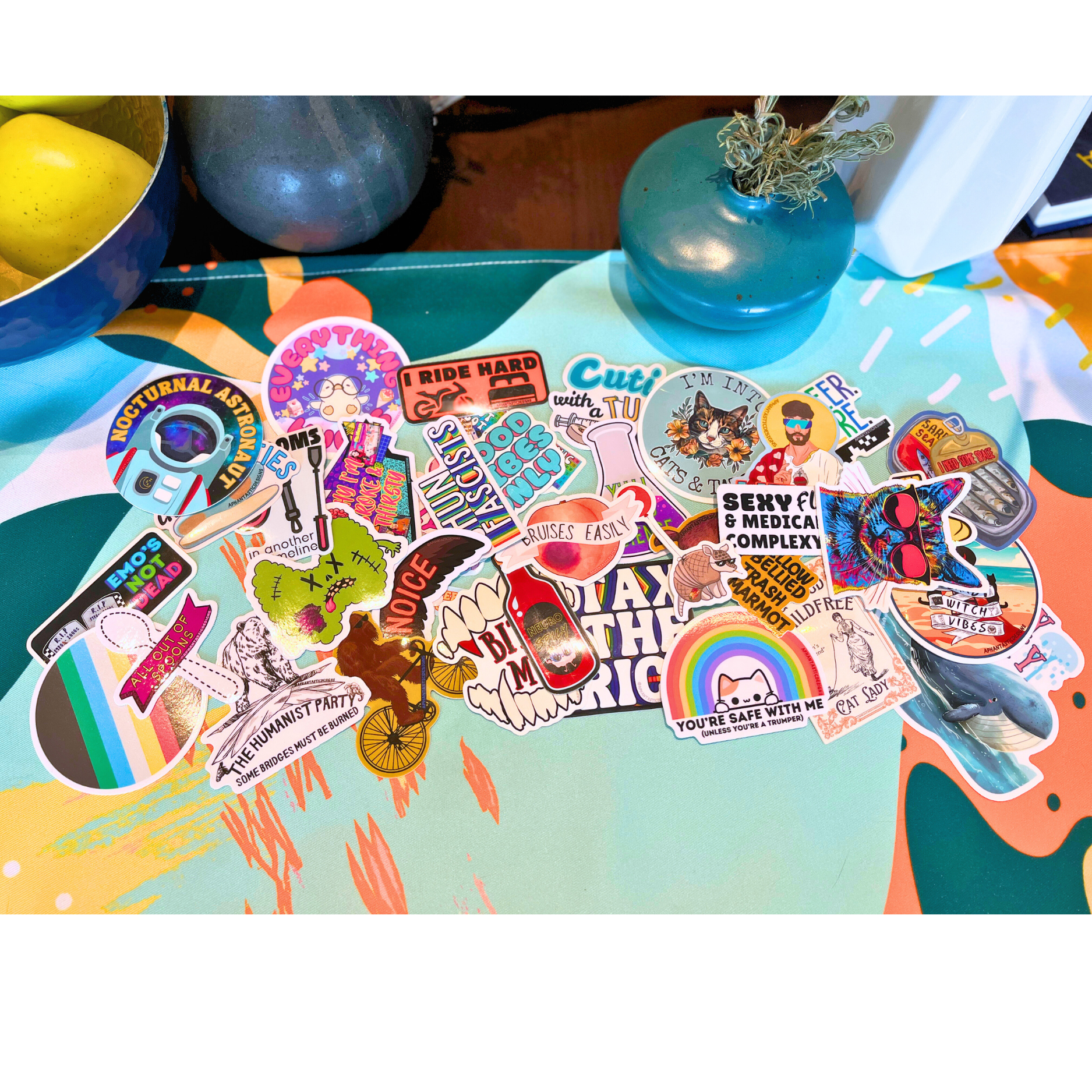 Collection of colorful stickers on a light green and orange background, featuring various designs including rainbows, animals, motivational phrases, and pop culture references.
