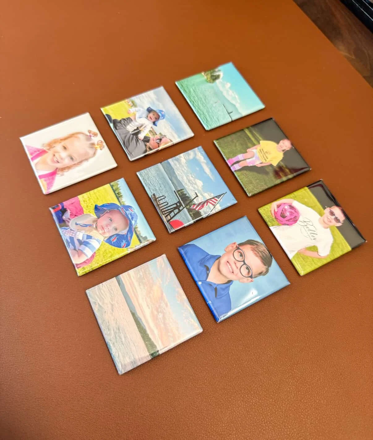Collection of eleven small photographs featuring children, landscapes, and flags, arranged on a wooden surface.