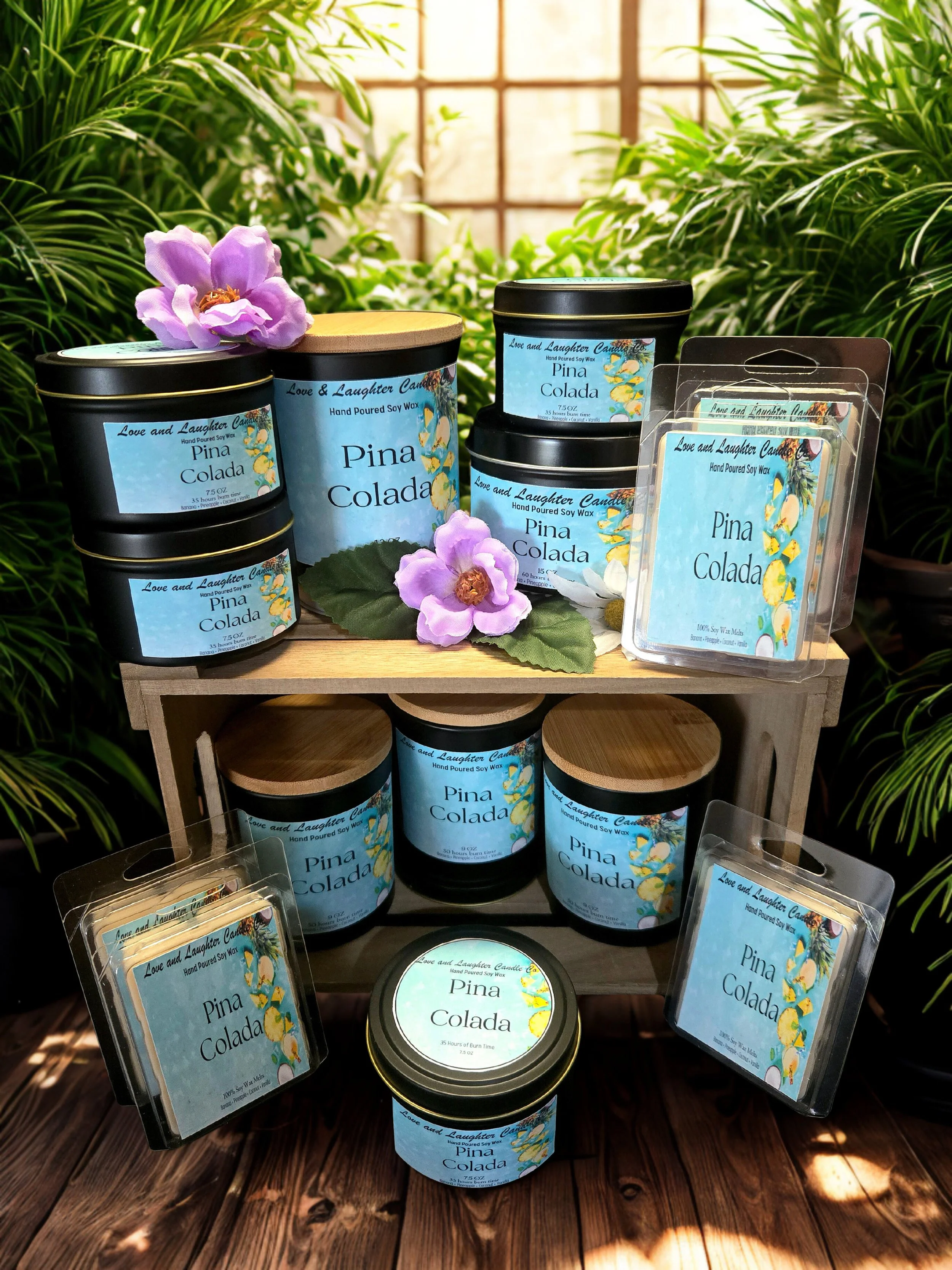 Display of candles and wax melts labeled 'Pina Colada' with tropical leaves and flowers in the background