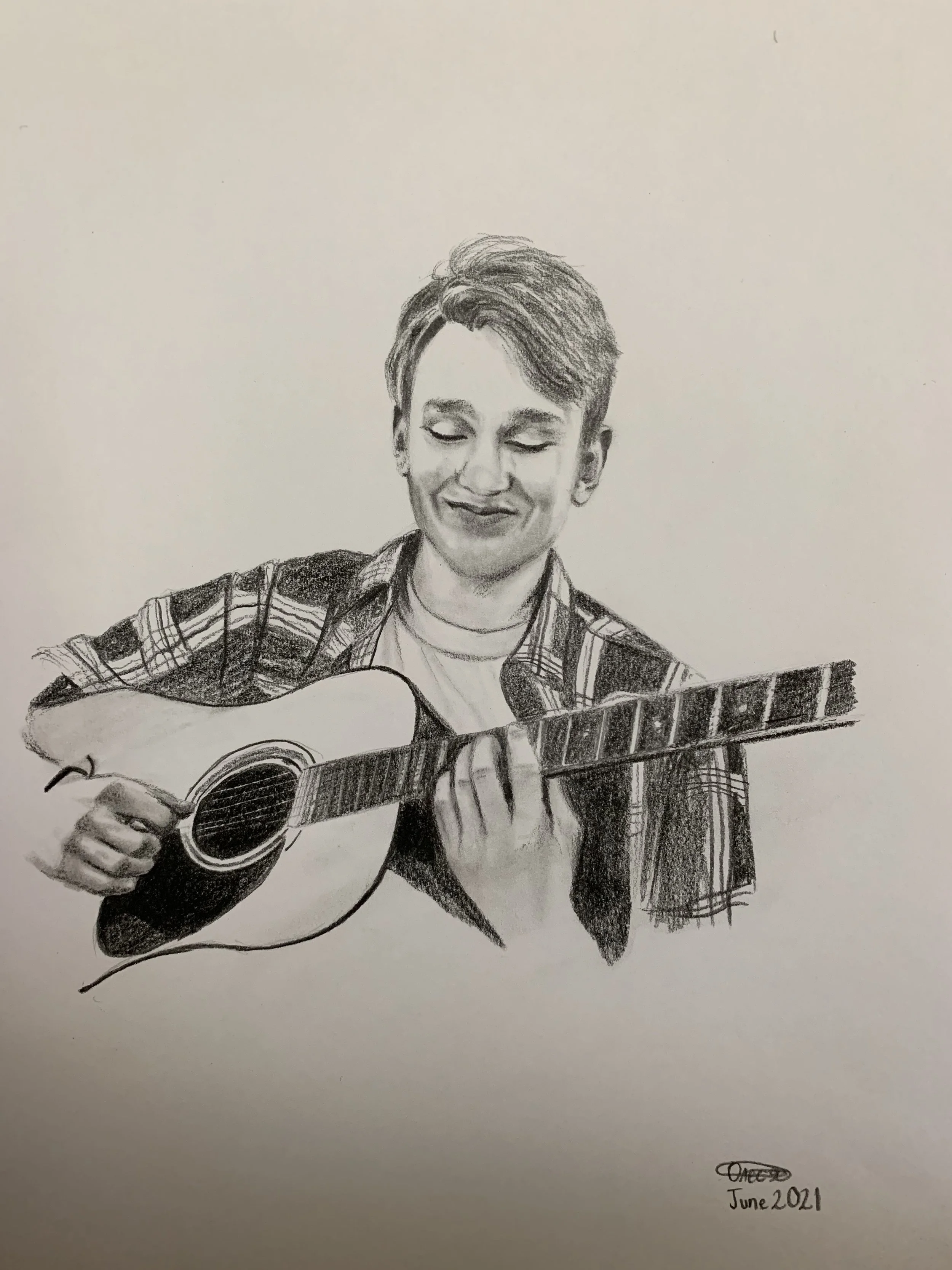 A pencil sketch of a young man playing an acoustic guitar, wearing a plaid shirt and smiling with eyes closed. The sketch is signed 'Omeg' and dated June 2021.