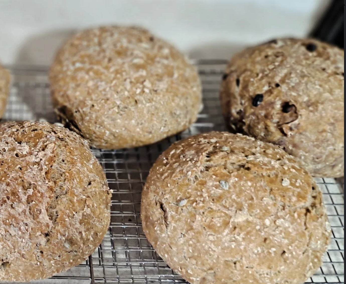 Close-up of four oatmeal cookies with dried fruit on a wire cooling rack