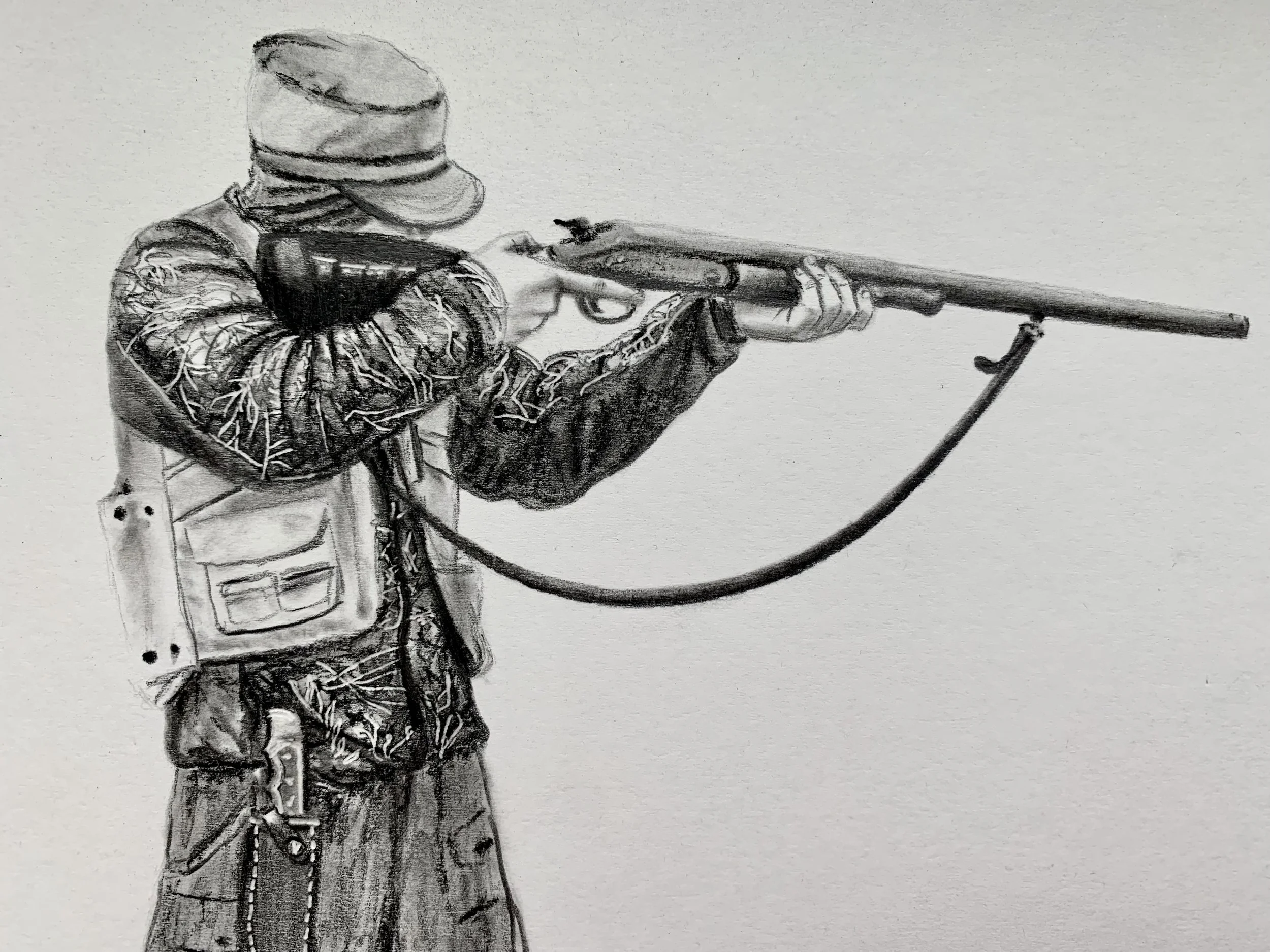 A child wearing a hat and a jacket with leaf patterns, aiming a rifle with both hands, standing outdoors.