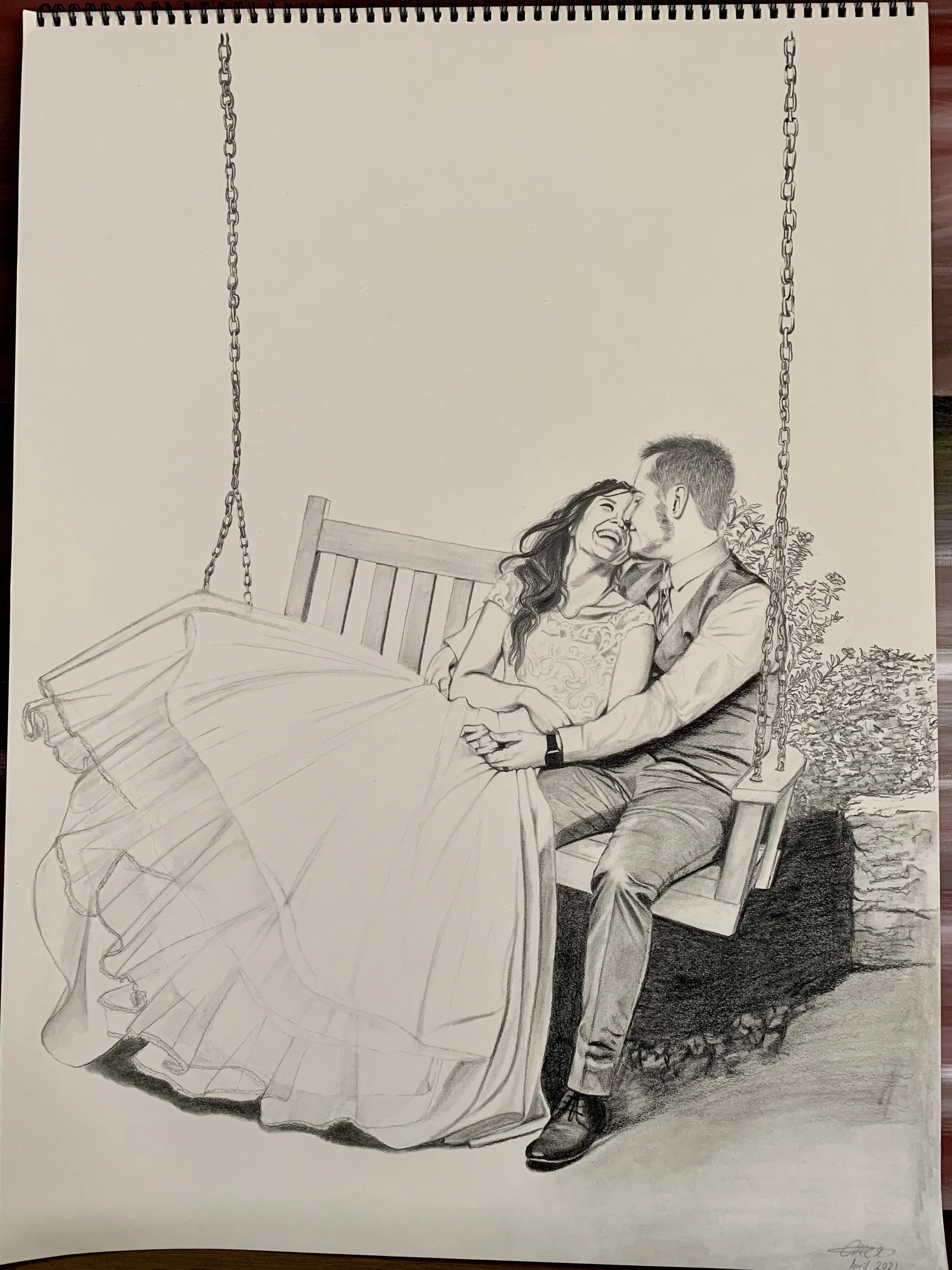 A pencil sketch of a joyful couple sitting on a swing bench, sharing a tender moment, with one woman laughing and the other man smiling, surrounded by a brick wall and some bushes.