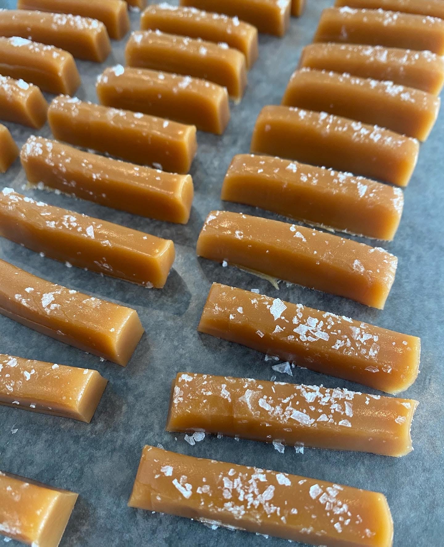 Rows of caramel candies sprinkled with sea salt on a baking sheet.