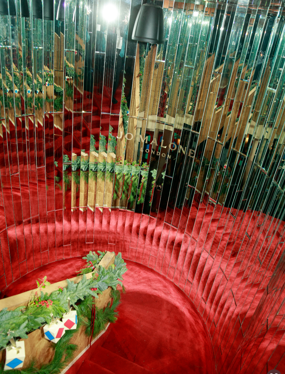 Red velvet circular staircase with festive Christmas decorations, greenery, and presents. Event design and production based in NYC.