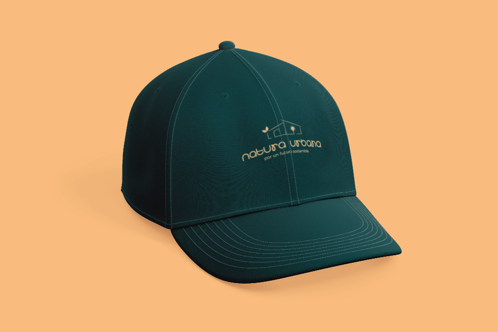 A dark green baseball cap with an embroidered logo and text that reads 'natura urbana' and 'por un futuro sostenible,' placed on a peach-colored background.