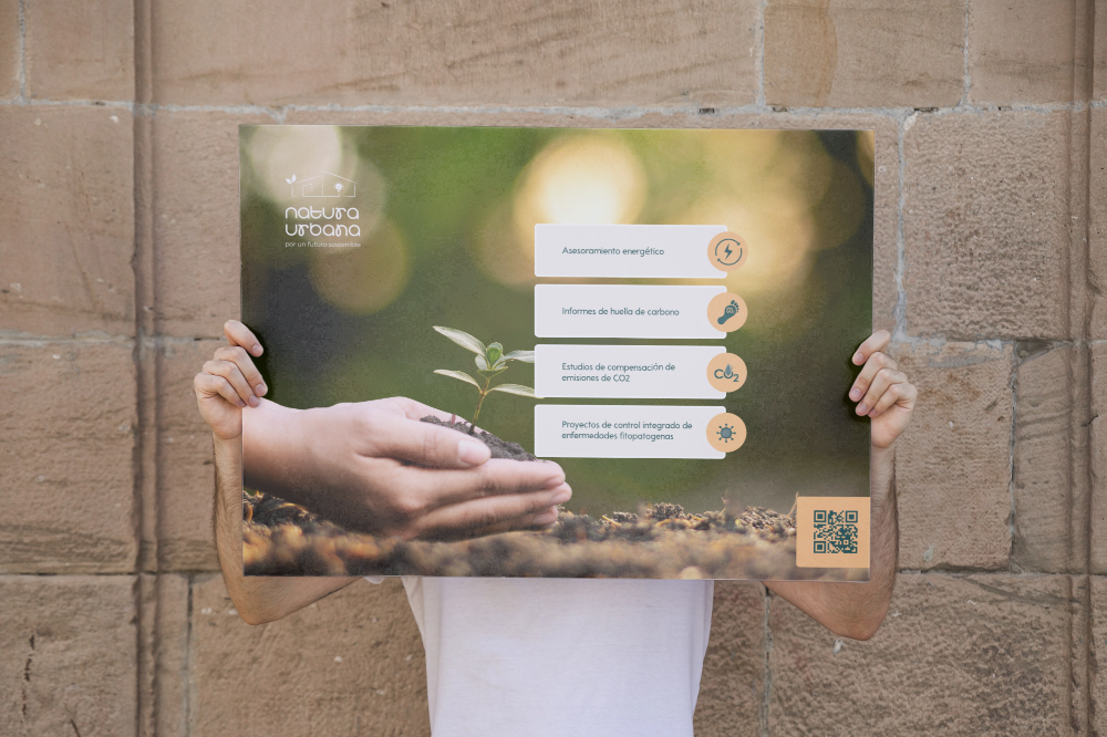 Person holding a poster about sustainability with a small plant in hand and a QR code.