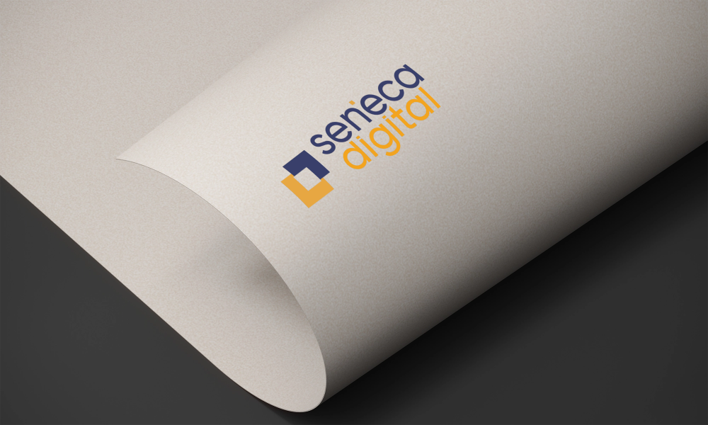 Close-up of a piece of paper with the Seneca Digital logo printed on it, showing the corner curled.